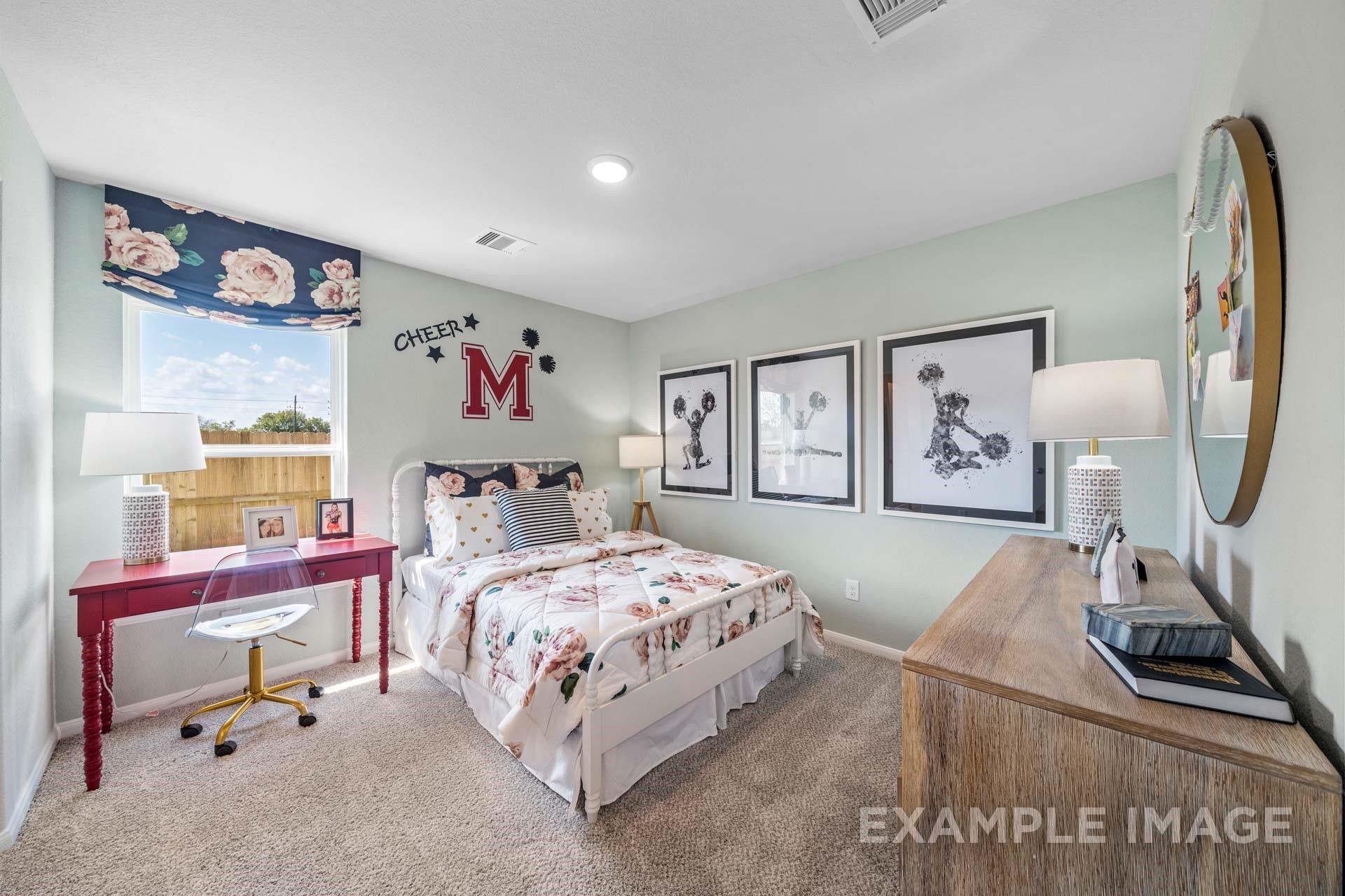 Cozy bedroom with floral bedding, desk, and cheer-themed decor in Davidson Homes Acadia A floor plan at Lago Mar, Texas City