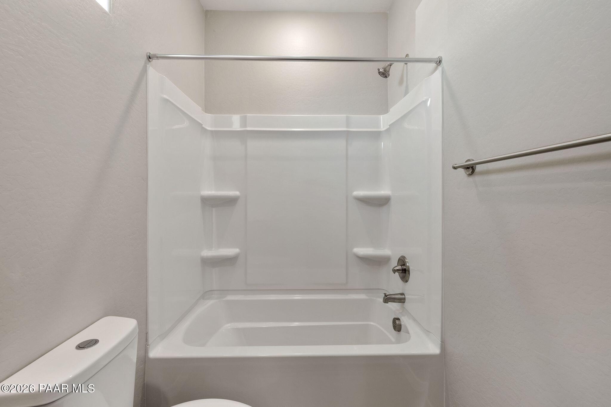 Modern white tub-shower combo with shelves and grab bars in Davidson Homes The Frontier A bathroom, Prescott Valley, Arizona