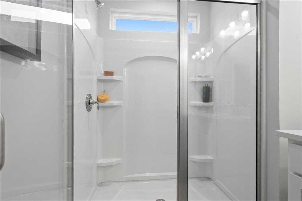 Modern white walk-in shower with frameless glass doors, arched niche, shelves and clerestory window in Davidson Homes Wilmington B, Emerson, GA