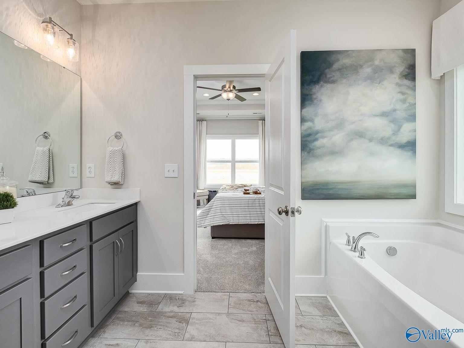 Elegant master bathroom with freestanding tub, double vanity, and open door to bedroom suite in Davidson Homes The Everett, Toney, AL