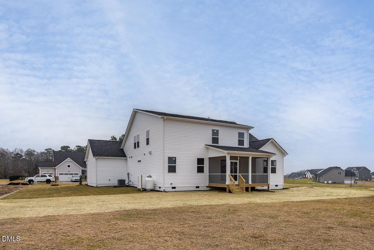 Modern 2-story white Cypress D II home with wrap-around porch, 3-car garage, and spacious yard in Tobacco Road, Angier, NC