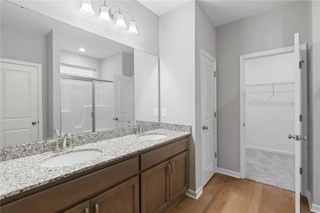 Modern master bathroom featuring double granite vanity, frameless shower, and walk-in closet in Davidson Homes The Luna B, Opelika