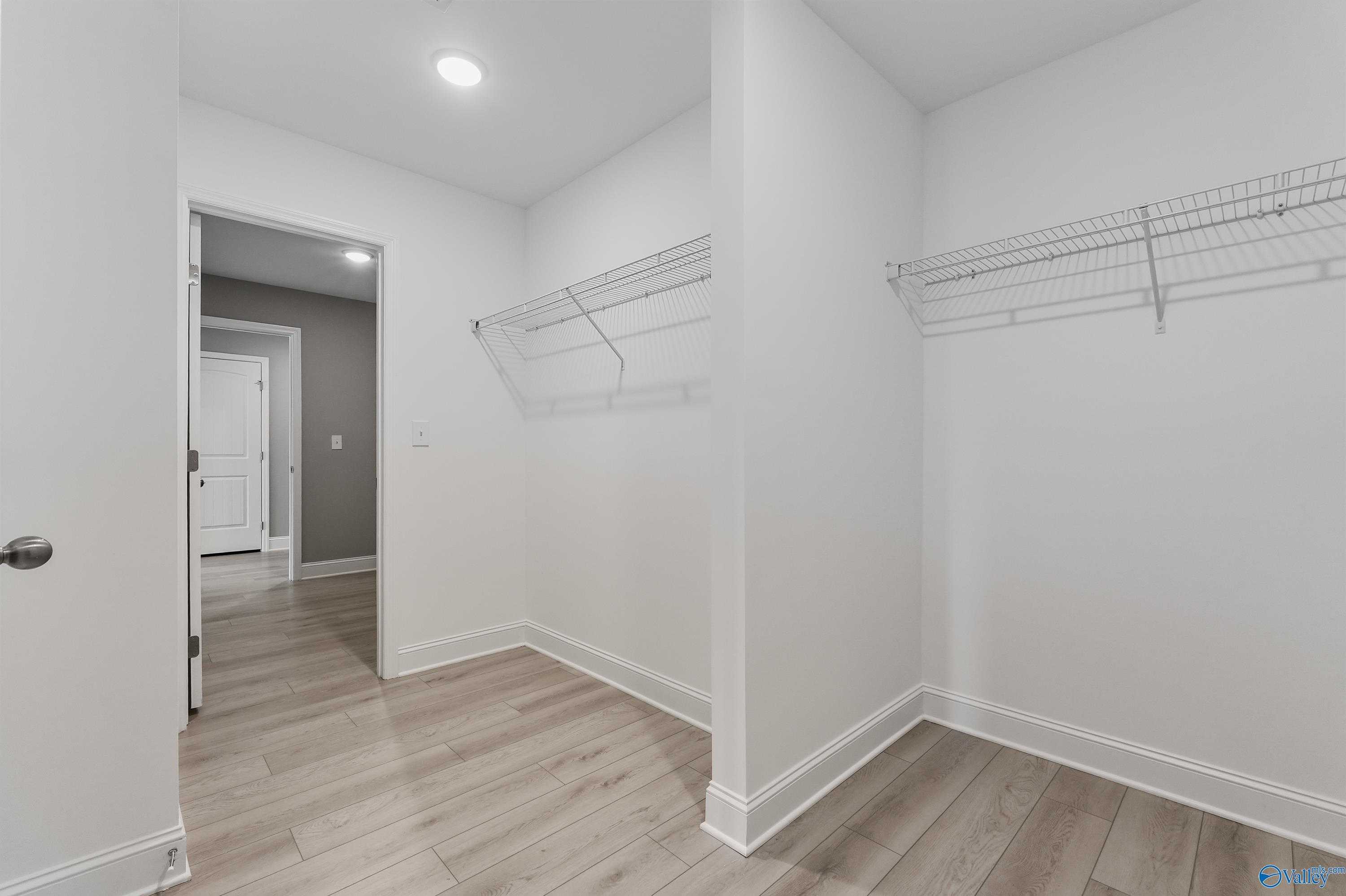 Spacious walk-in closet with wire shelving, hardwood floors in master suite of Davidson Homes The Everett B, Athens, Alabama