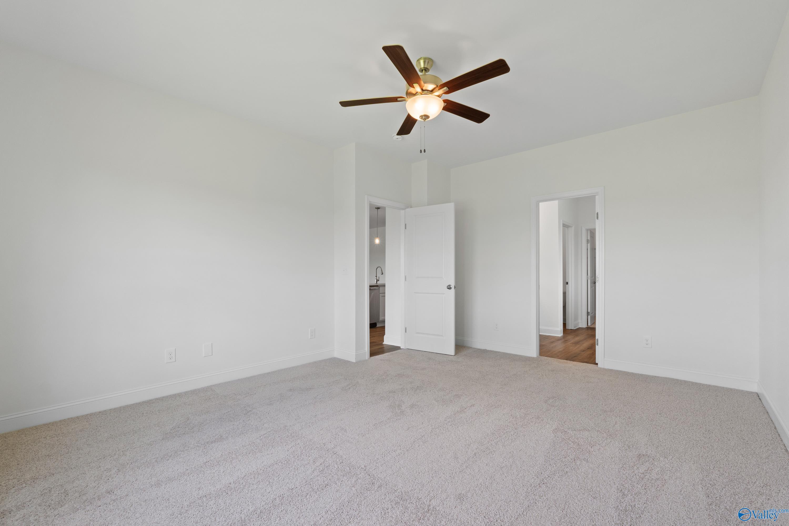 Spacious bedroom with ceiling fan and plush neutral carpet in The Everett B floor plan at The Meadows, Athens, Alabama.