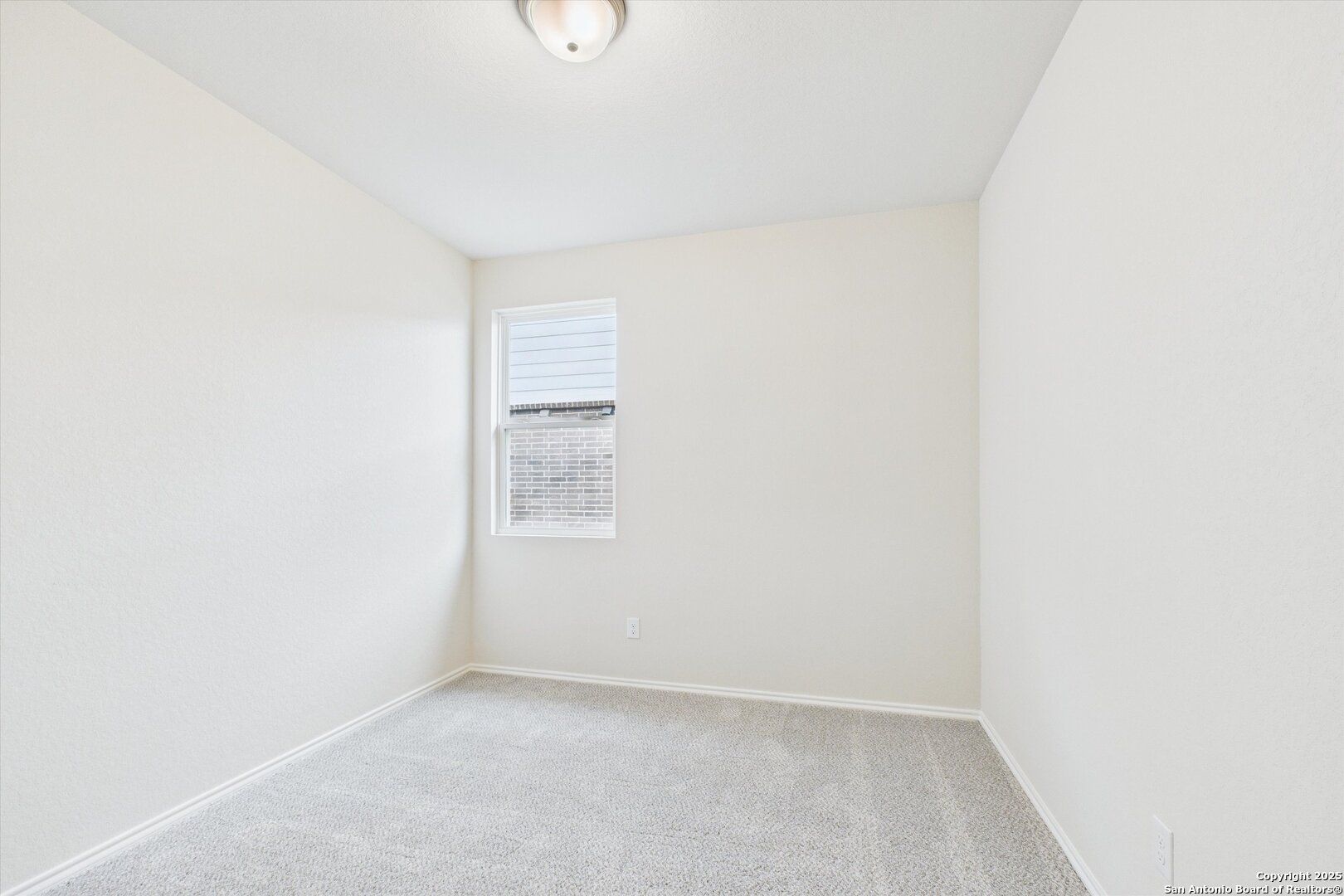 Bright secondary bedroom with beige carpet, white walls, and large window in Davidson Homes The Asheville K, San Antonio