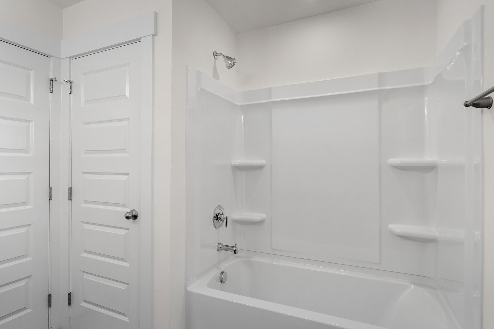 Bright white bathroom with soaking tub, glass shower enclosure, and built-in shelves in Davidson Homes The Willow C, Gallatin, Tennessee