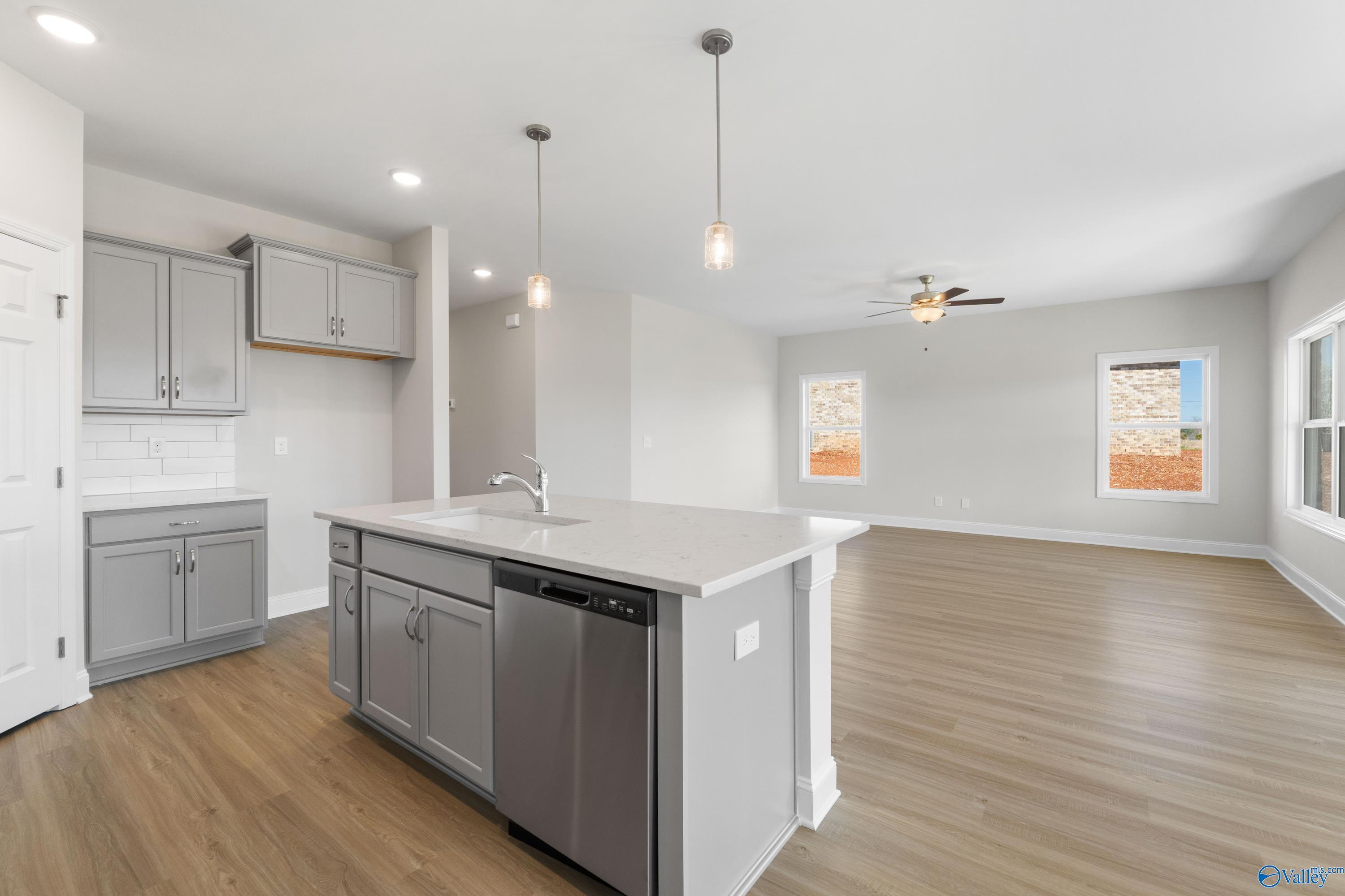 Modern gray kitchen with quartz island, stainless dishwasher, subway tile backsplash in The Franklin C, Davidson Homes, Athens AL
