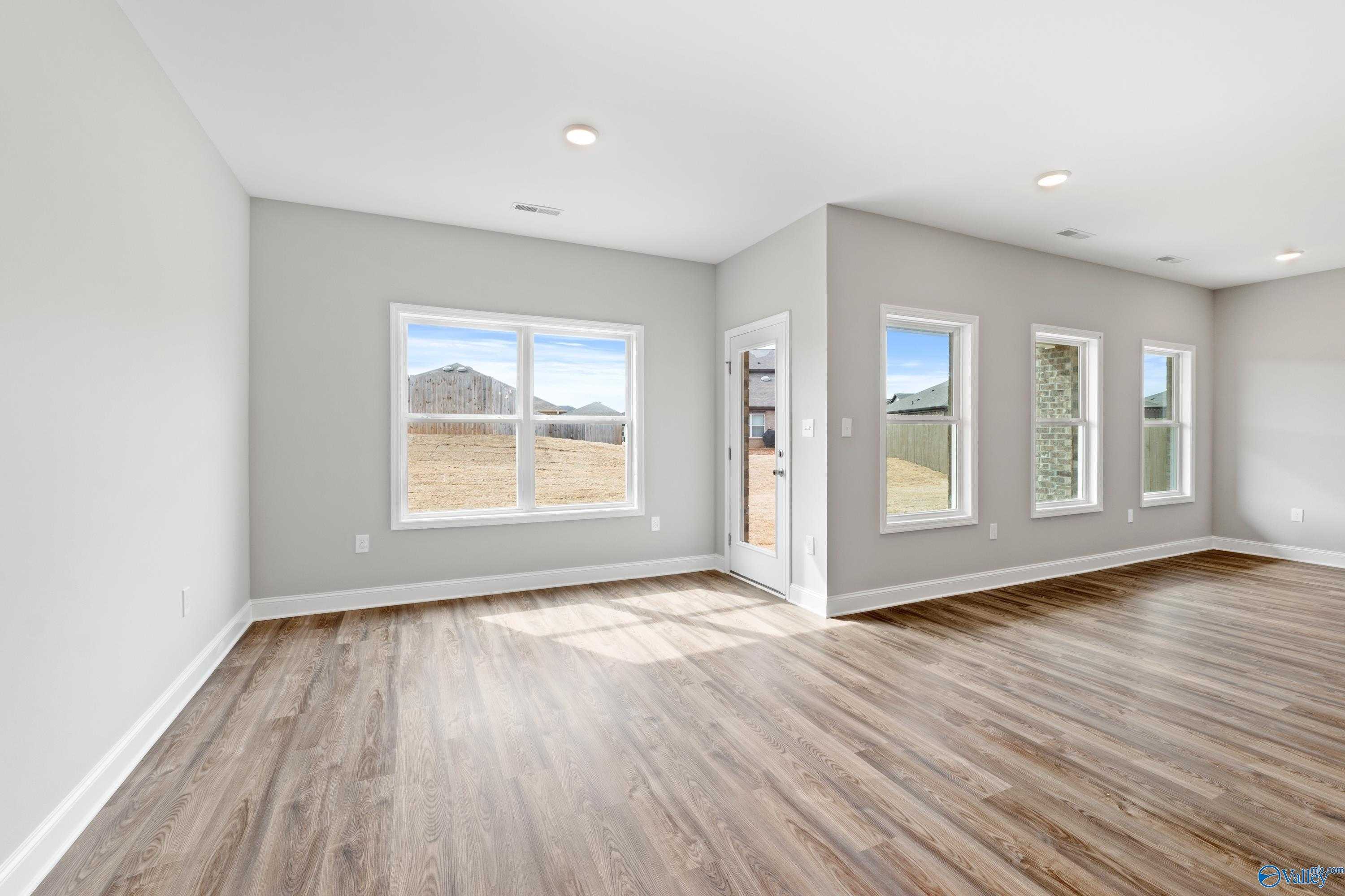 Bright open living room with hardwood floors, gray walls, and large windows to backyard in Davidson Homes The Aiken, Meridianville, AL