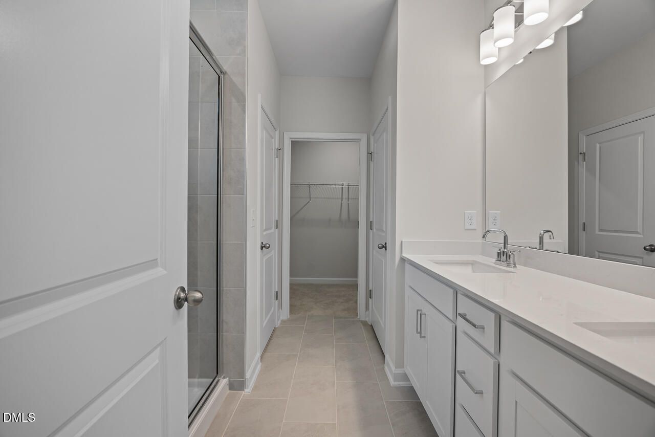Primary bathroom with dual vanity, walk-in shower, and walk-in closet in Davidson Homes The Daphne D, Zebulon, NC