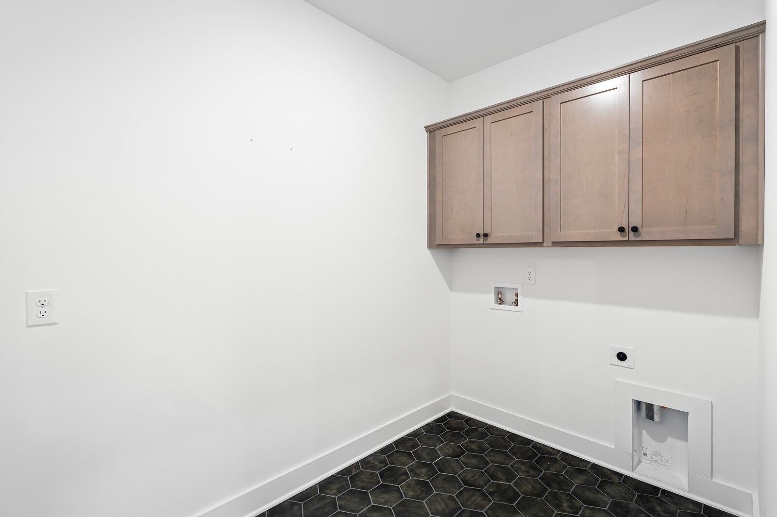 Bright laundry room with shaker upper cabinets and black hexagonal tile floor in Davidson Homes Ridgeport, Gallatin, TN