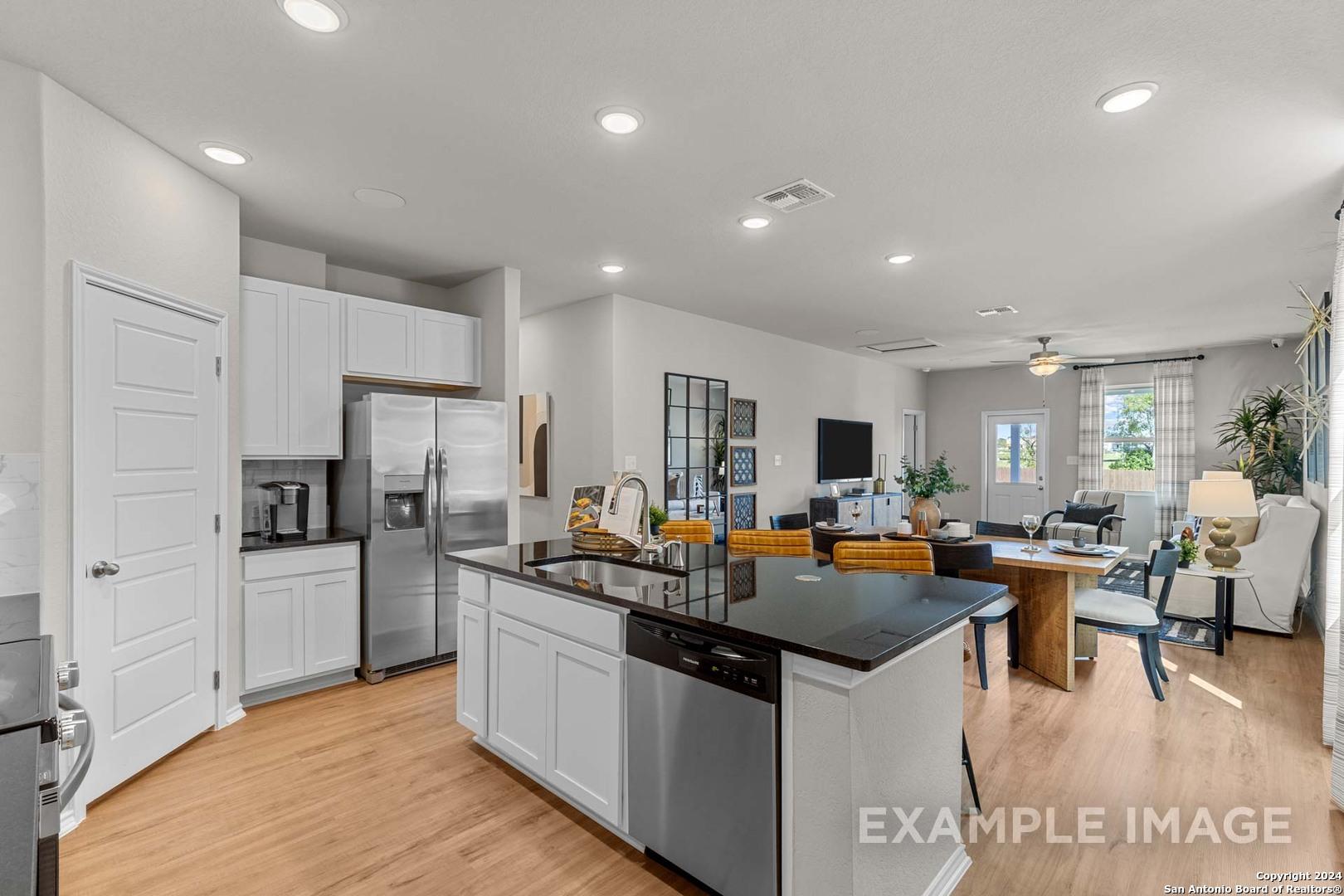 Modern open-concept kitchen with black granite island, stainless appliances, and dining nook in Davidson Homes The Sabine B, San Antonio