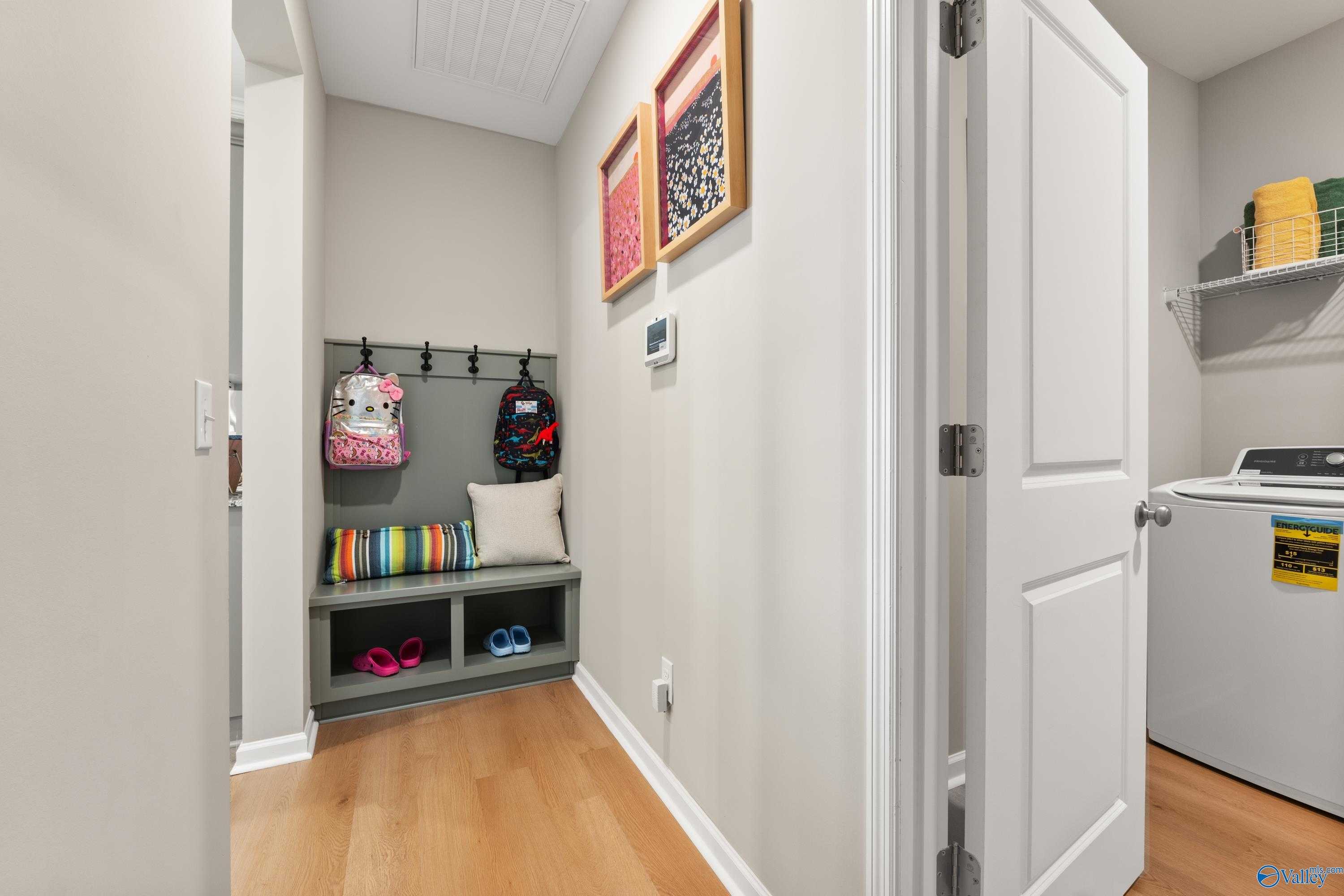 Functional mudroom with backpack hooks, storage bench, and laundry area in Davidson Homes The Sanctuary, Athens, Alabama