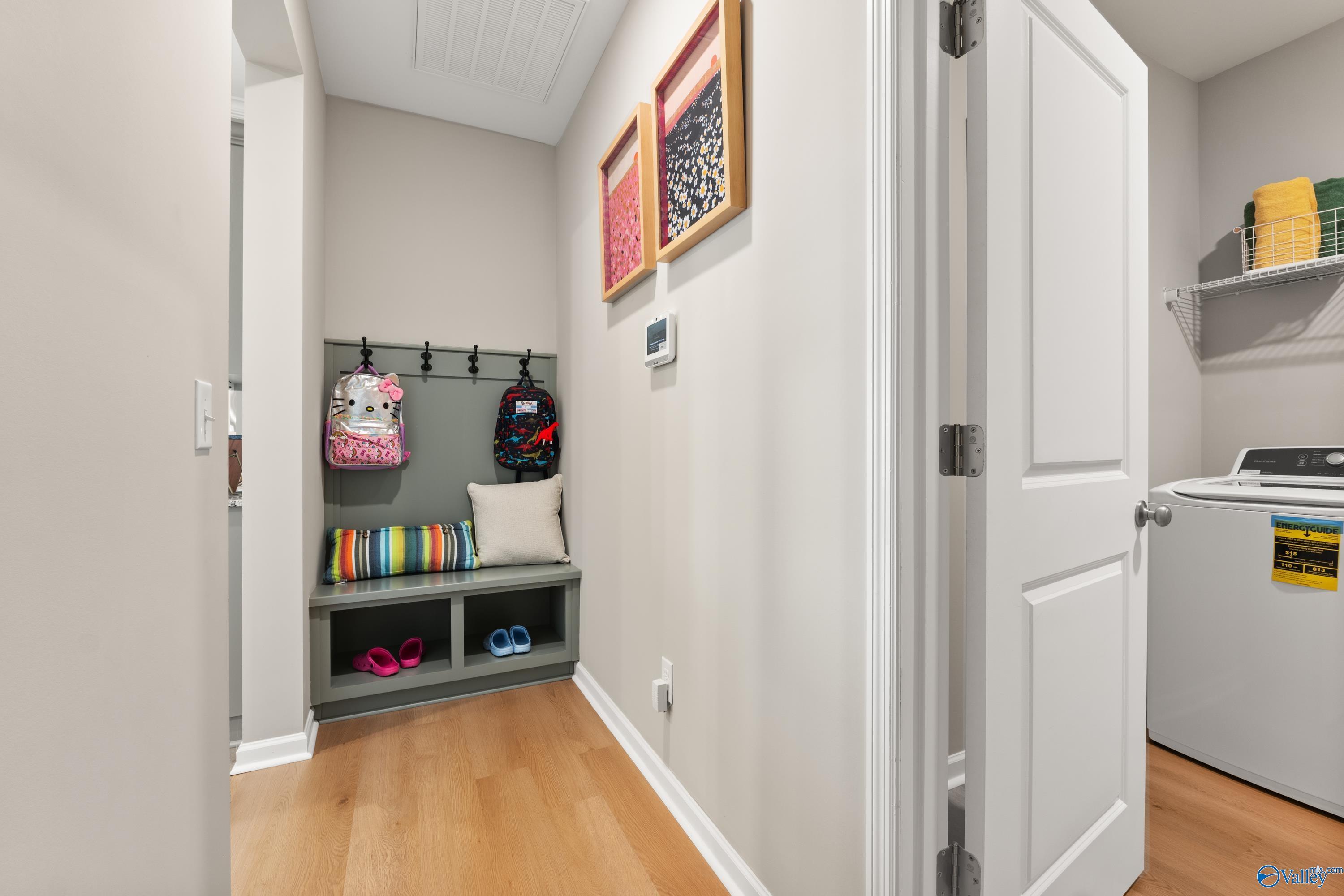 Functional mudroom with backpack hooks, storage bench, and laundry area in Davidson Homes The Sanctuary, Athens, Alabama