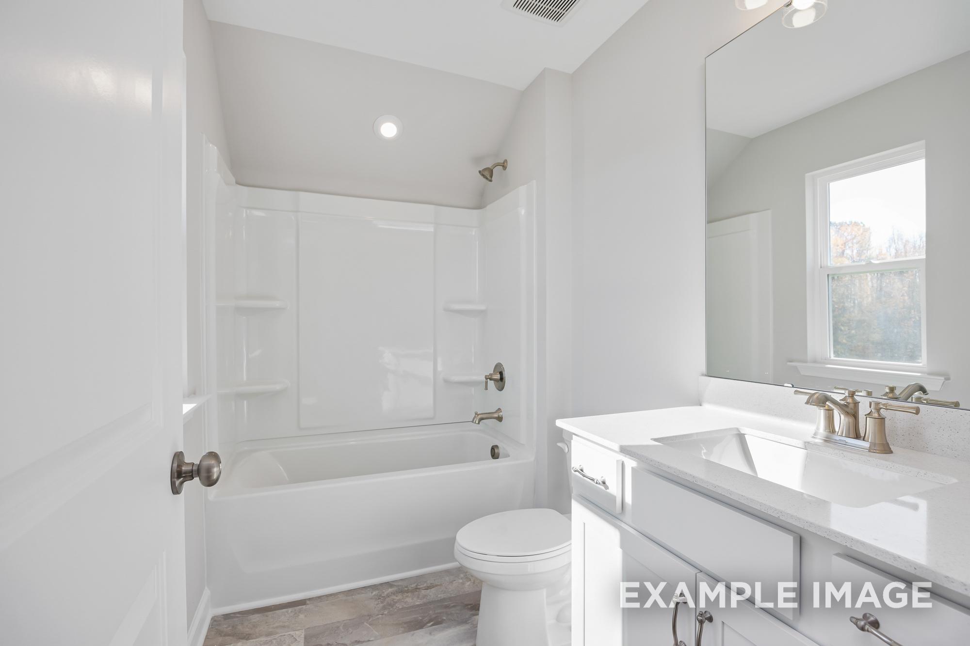 Spacious master bathroom in The Cypress C II with white tub, glass shower, double vanity, large mirror, and window