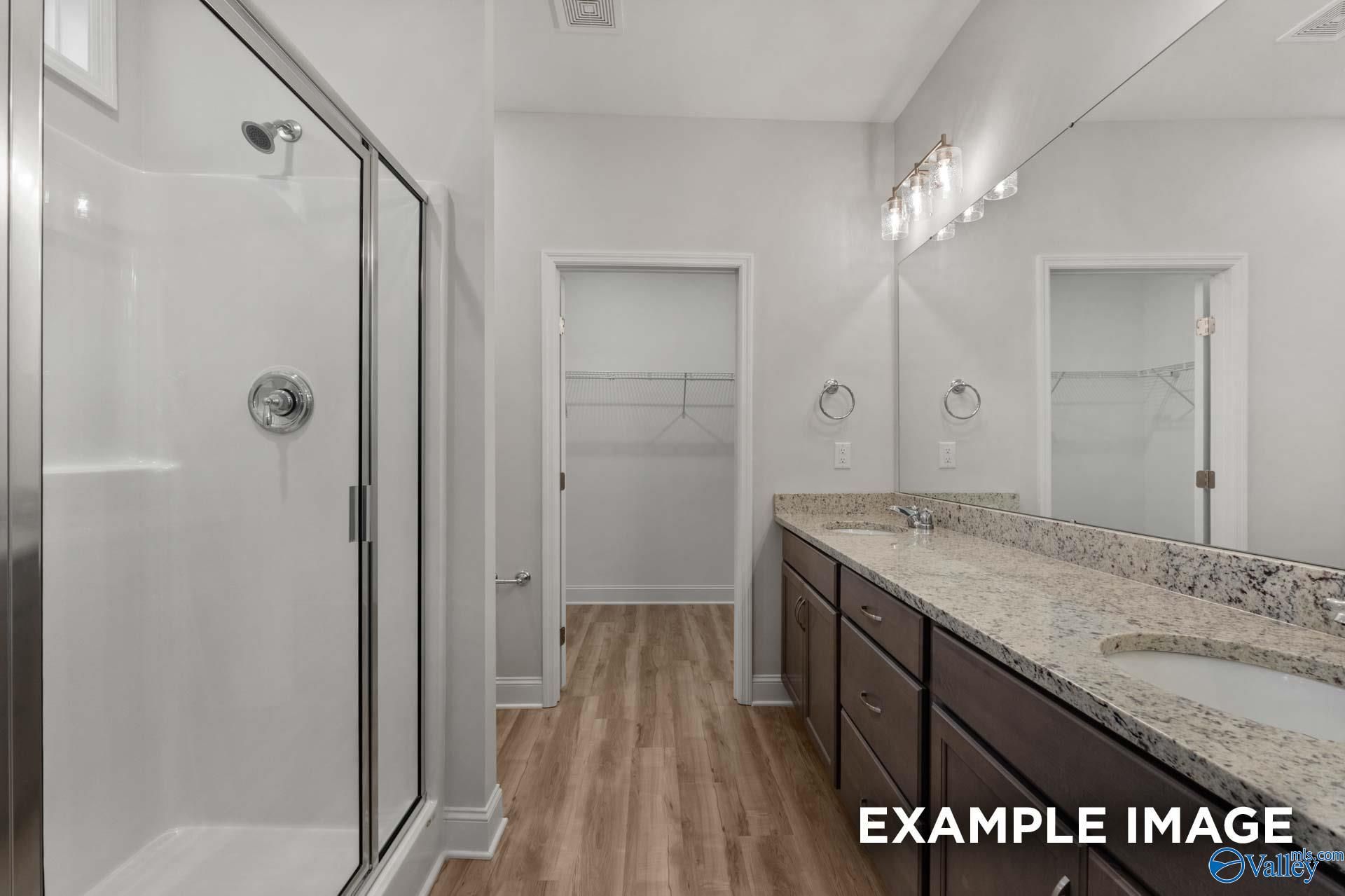 Modern master bathroom featuring glass shower, granite vanity, double sinks, and walk-in closet in Davidson Homes The Cumberland B, Decatur, AL