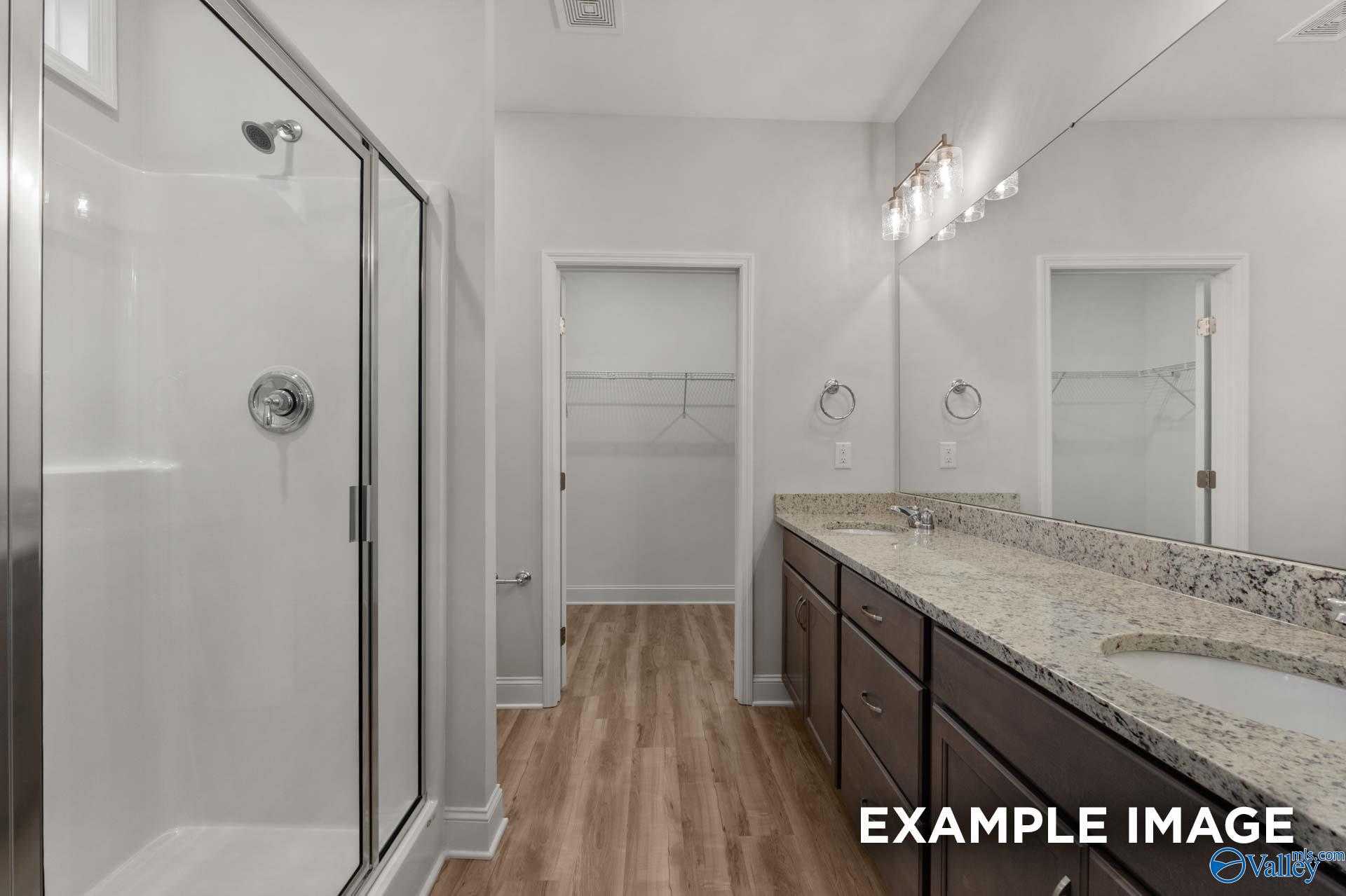 Modern master bathroom featuring glass shower, granite vanity, double sinks, and walk-in closet in Davidson Homes The Cumberland B, Decatur, AL