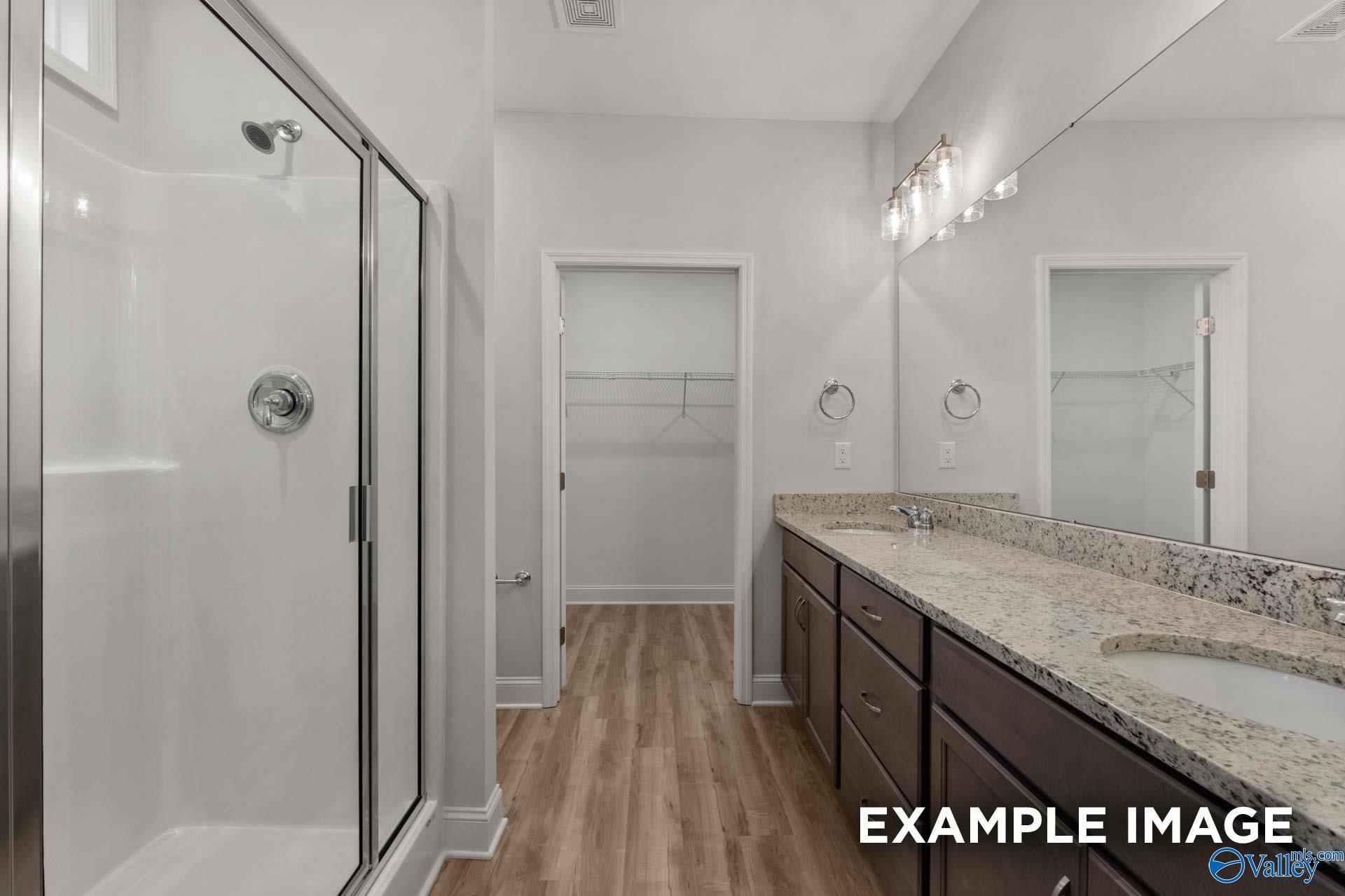 Modern master bathroom featuring glass frameless shower, double granite vanity, and walk-in closet in Davidson Homes The Cumberland B, Decatur AL