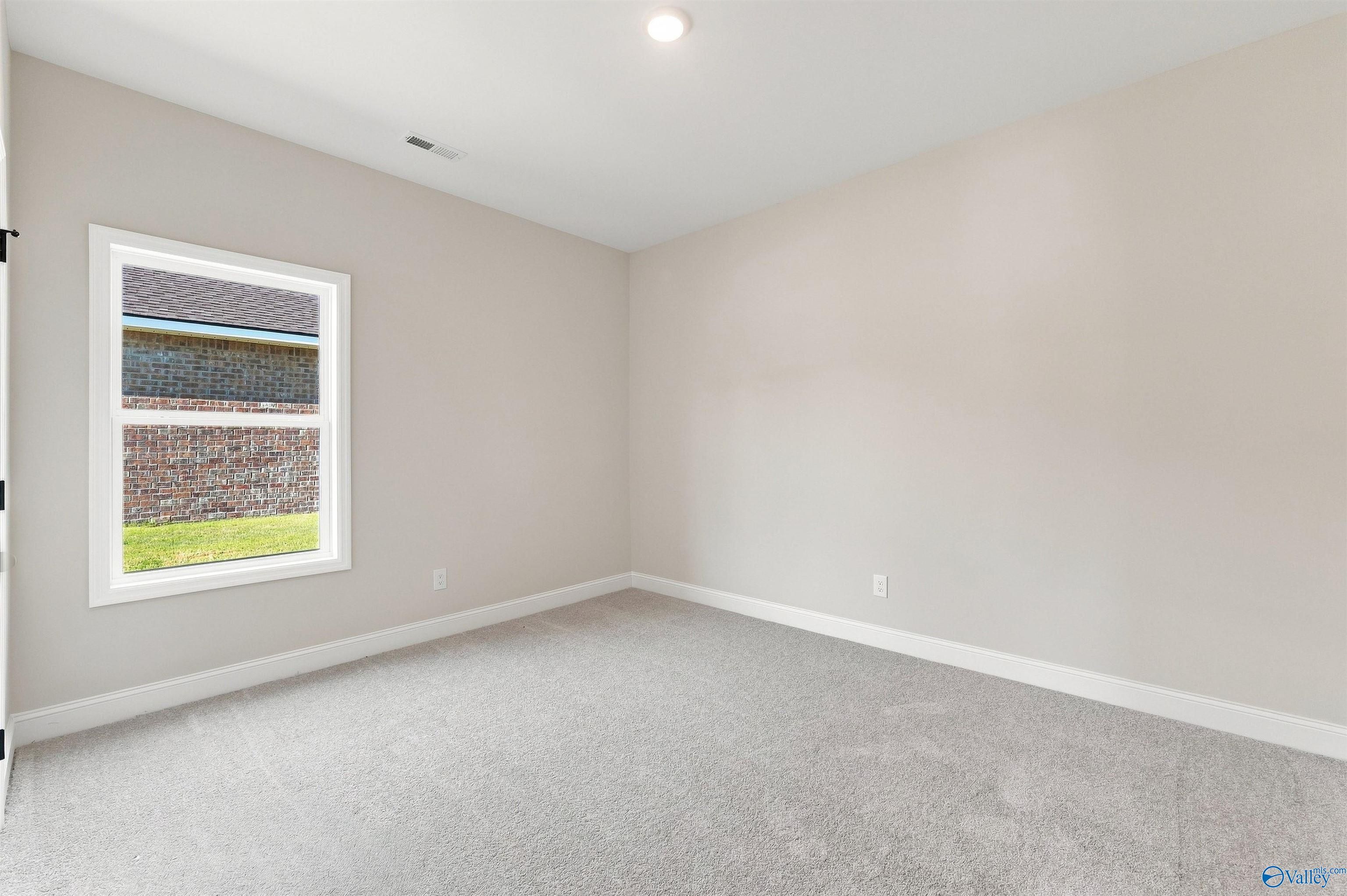 Bright, carpeted bedroom in The Daphne floor plan by Davidson Homes at Spragins Cove in Huntsville, Alabama.