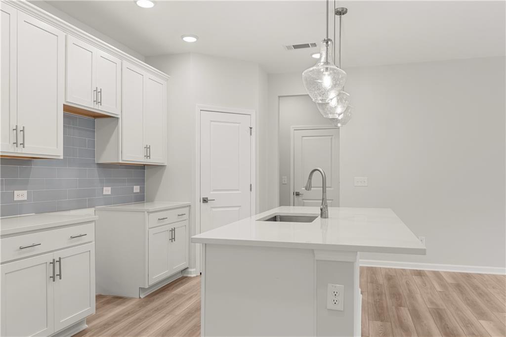 Modern kitchen with white cabinets, quartz island, and pendant lighting in The Russell A floor plan at Cedar Farms, Winder.