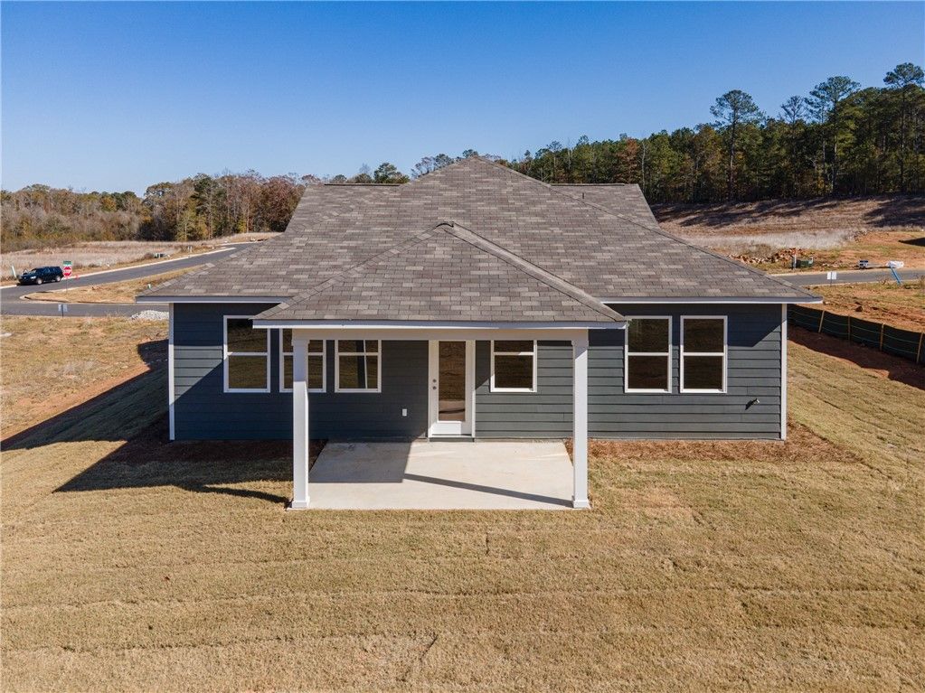 Rear view of gray single-story The Luna B home by Davidson Homes, covered patio, large windows, wooded lot in Anderson Lakes, Opelika, Alabama
