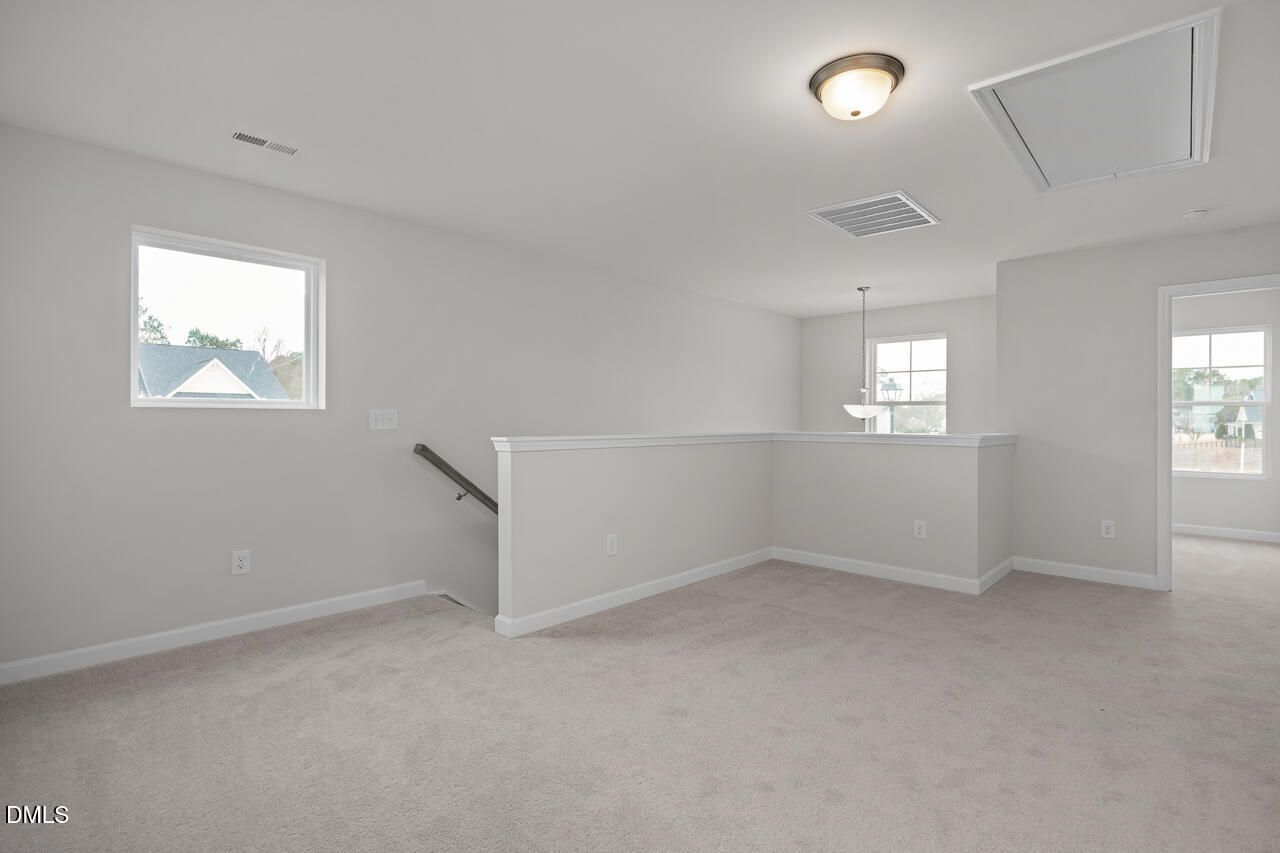 Spacious upstairs loft with neutral carpet, light gray walls, and staircase overlook in Davidson Homes The Gavin B, Lillington, NC