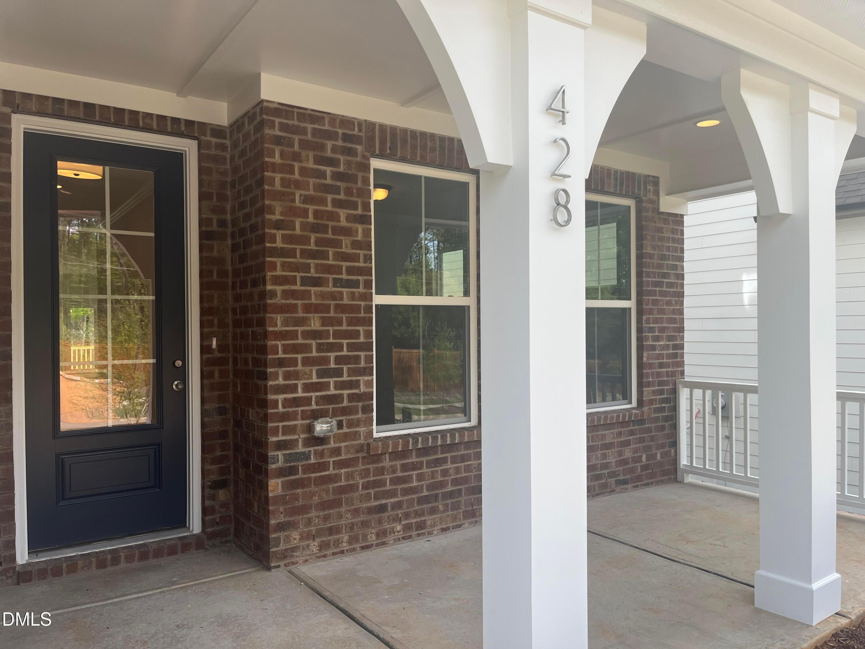 Charming brick facade with covered porch, white columns, and black front door on Davidson Homes Ashport L in Wake Forest, NC