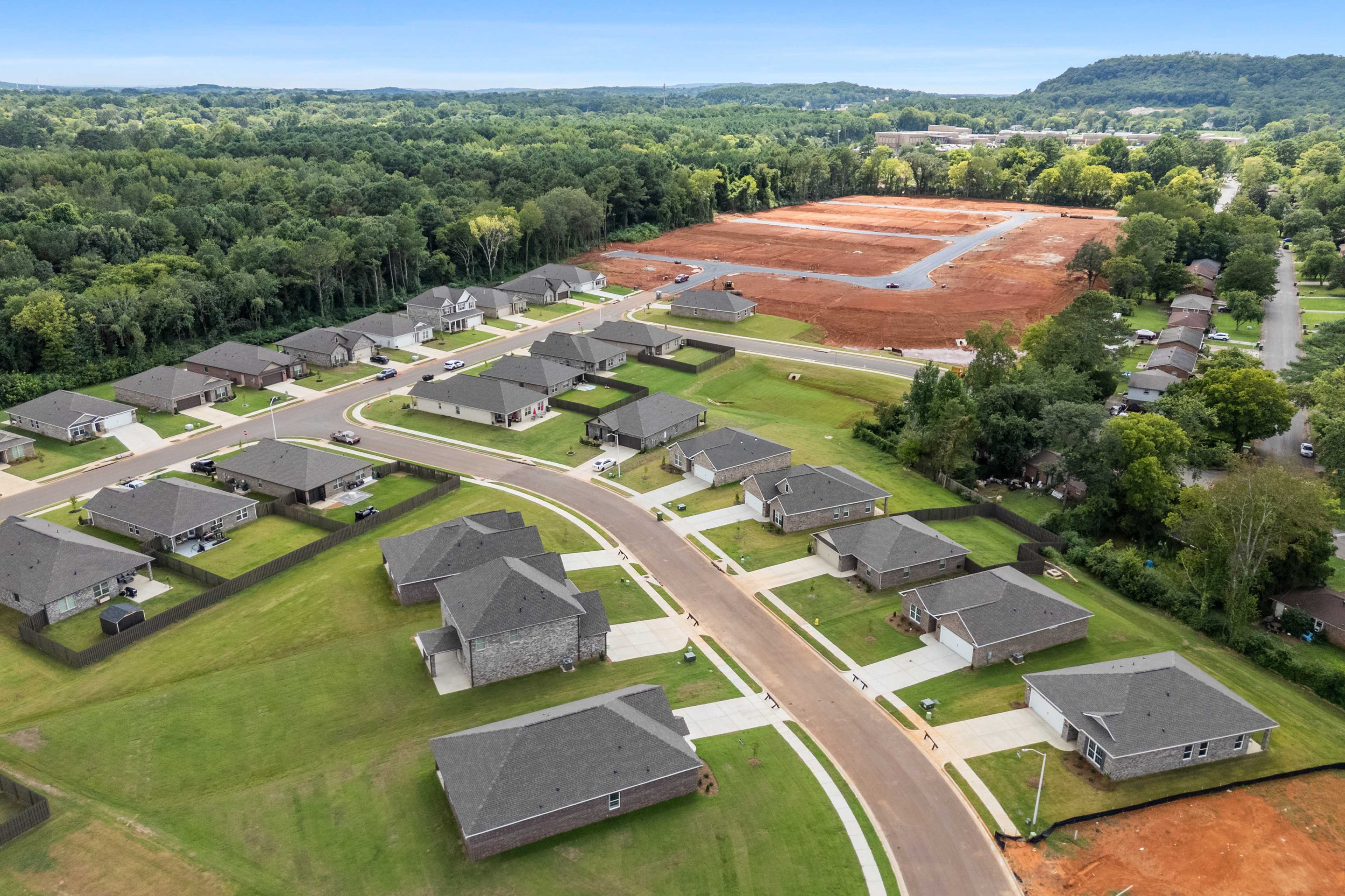 Aerial view of new homes in Blue Spring Huntsville AL with construction sites, green lawns, and surrounding forests