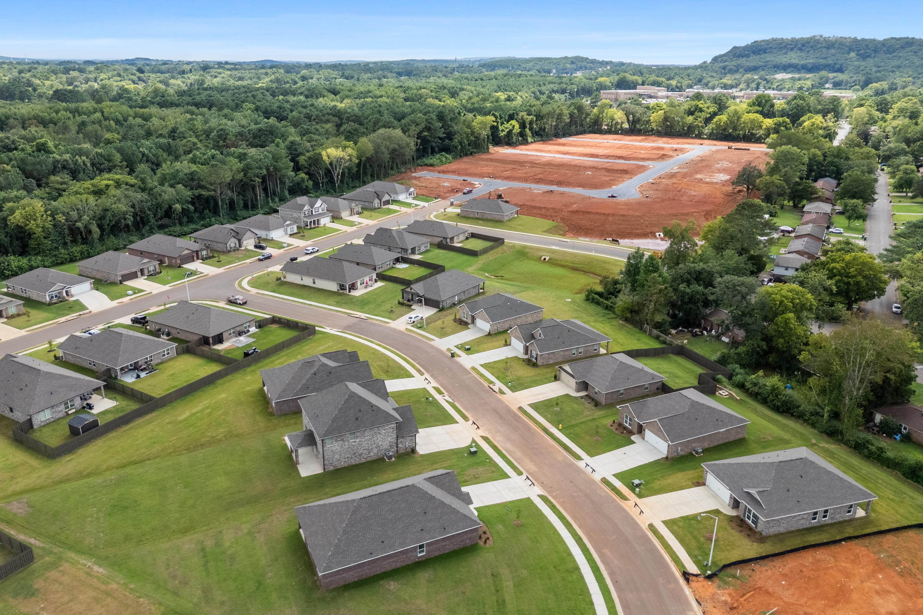 Aerial view of new homes in Blue Spring Huntsville AL with construction sites, green lawns, and surrounding forests
