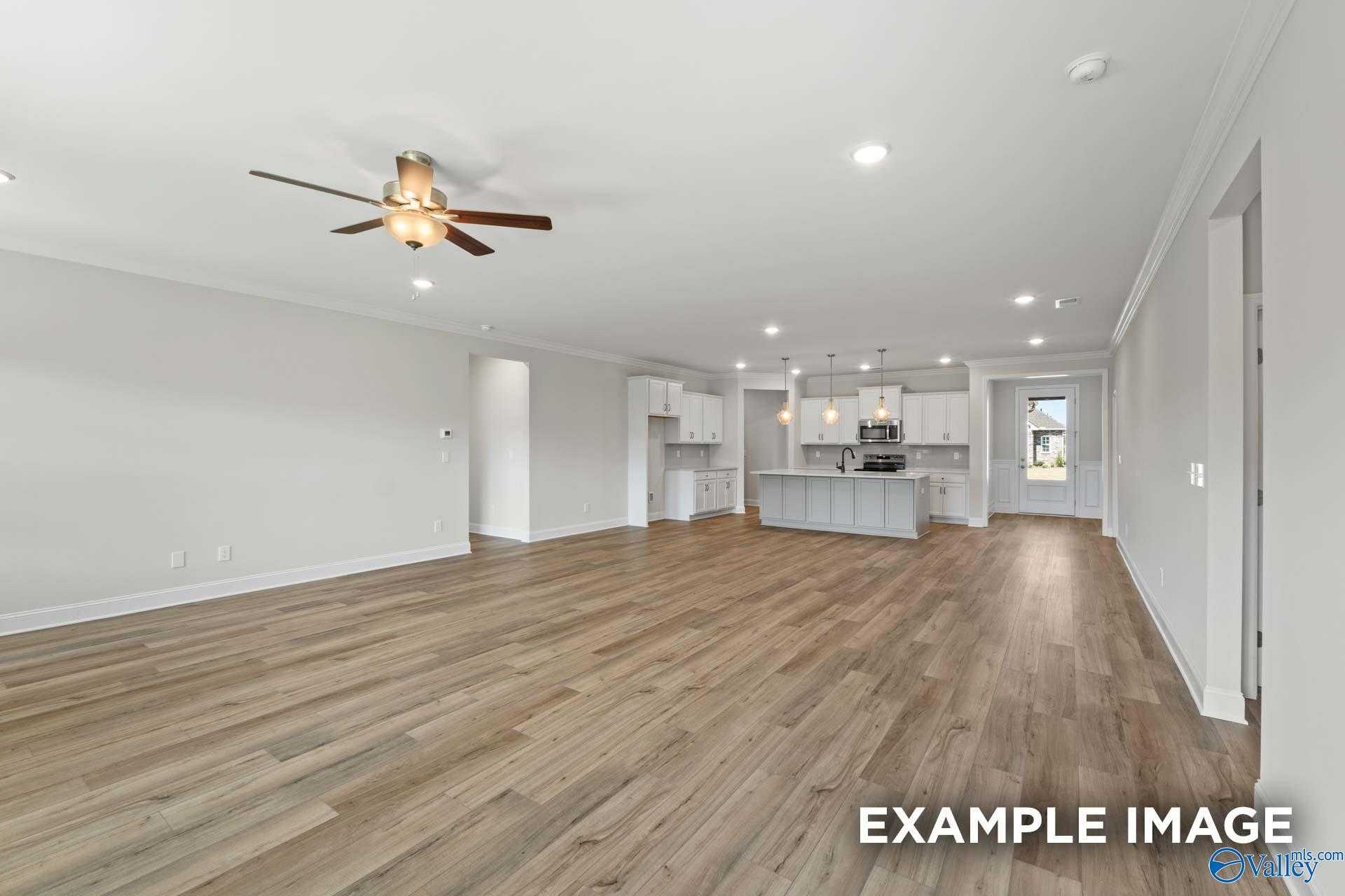Open-concept great room with hardwood floors, white kitchen island, and recessed lighting in The Lanier by Davidson Homes, Toney, AL