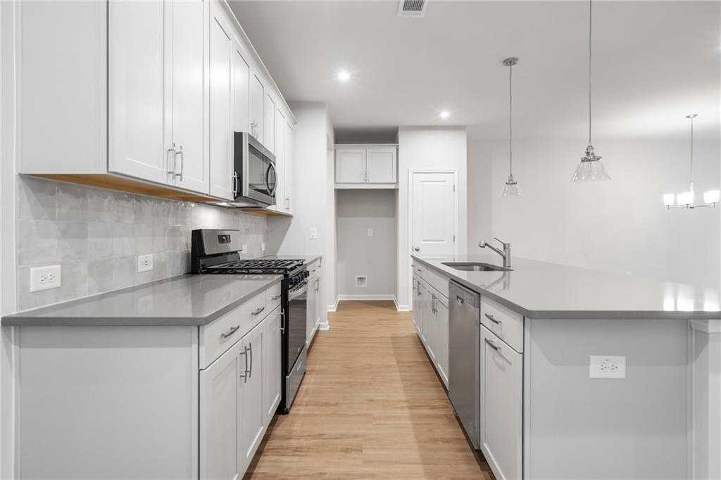 Bright open-concept kitchen with white shaker cabinets, gray quartz island, subway tile backsplash, and stainless appliances in The Cary A floor plan, Kennesaw, Georgia
