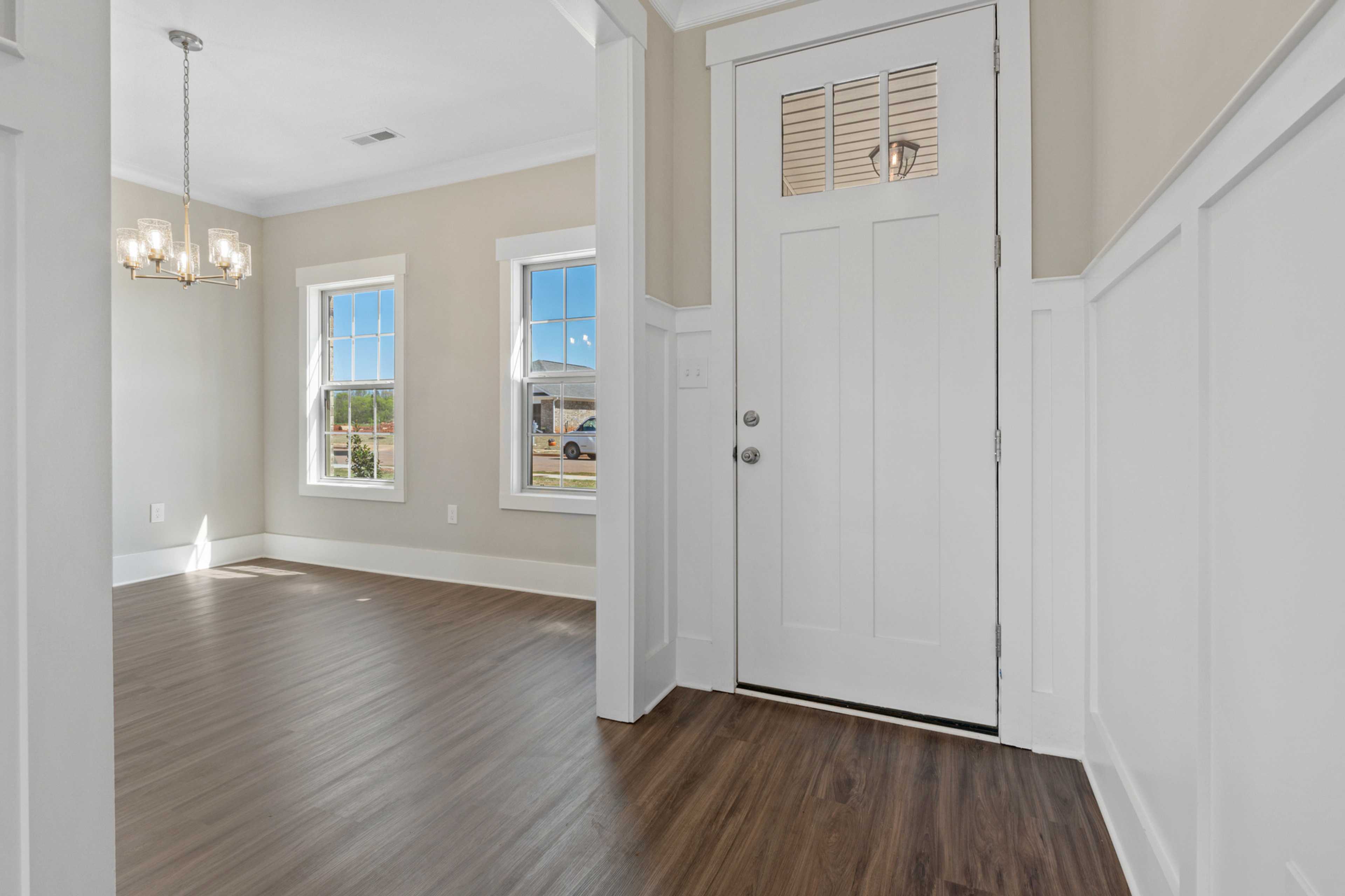 Bright entry foyer at Little Burwell Estates in Harvest Alabama with chandelier, hardwood floors, and large windows