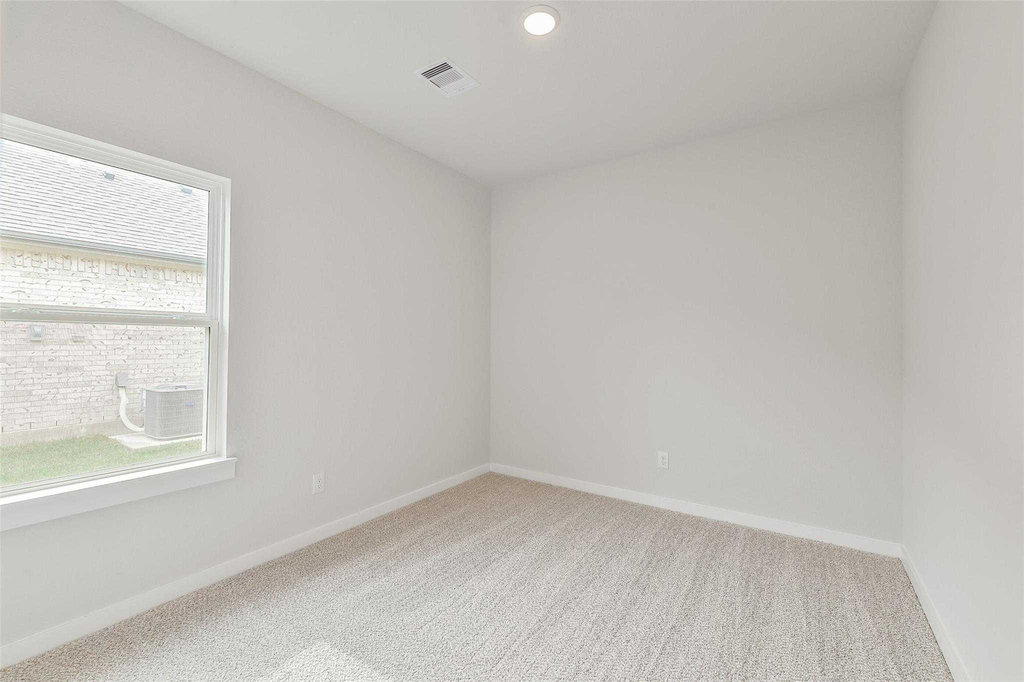 Bright secondary bedroom with large window, neutral walls, and carpeted floor in Davidson Homes The Colorado G, Magnolia, Texas