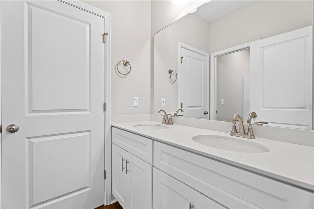 Modern double vanity bathroom with white shaker cabinets, chrome faucets, and mirrors in Evermore Homes The Orion, Cusseta, Alabama