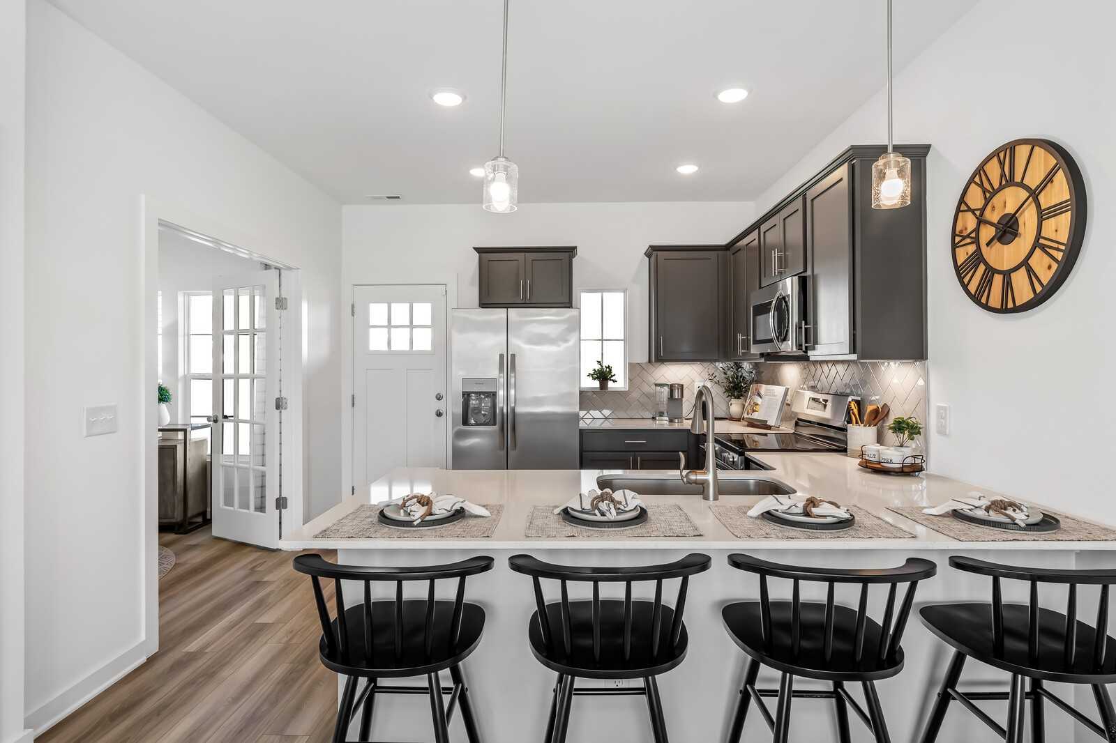 Modern kitchen with shaker cabinets, stainless appliances, bar island, and pendant lights in Davidson Homes The Cumberland B, Gallatin, TN