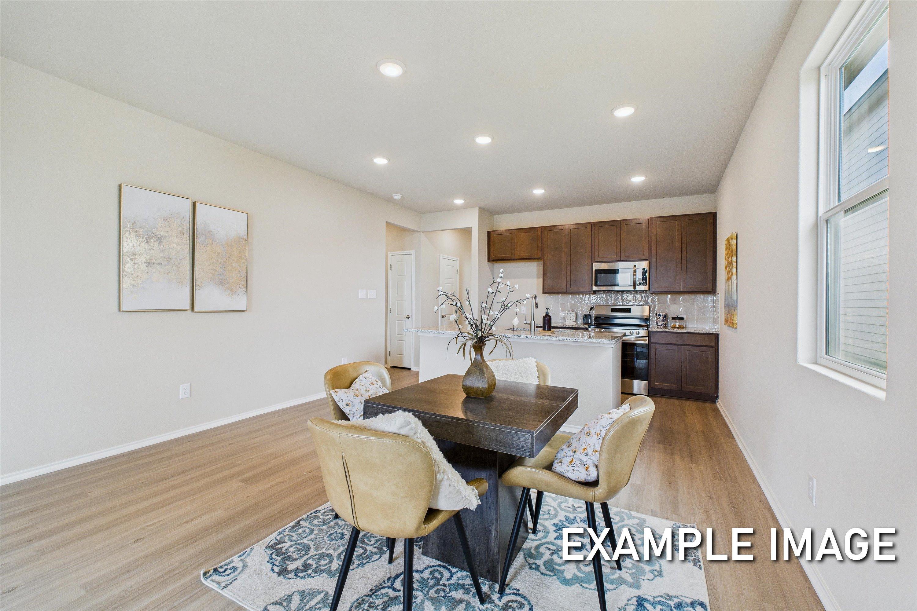 Open-concept kitchen and dining area in The Comal floor plan featuring dark wood cabinets and a modern breakfast nook.