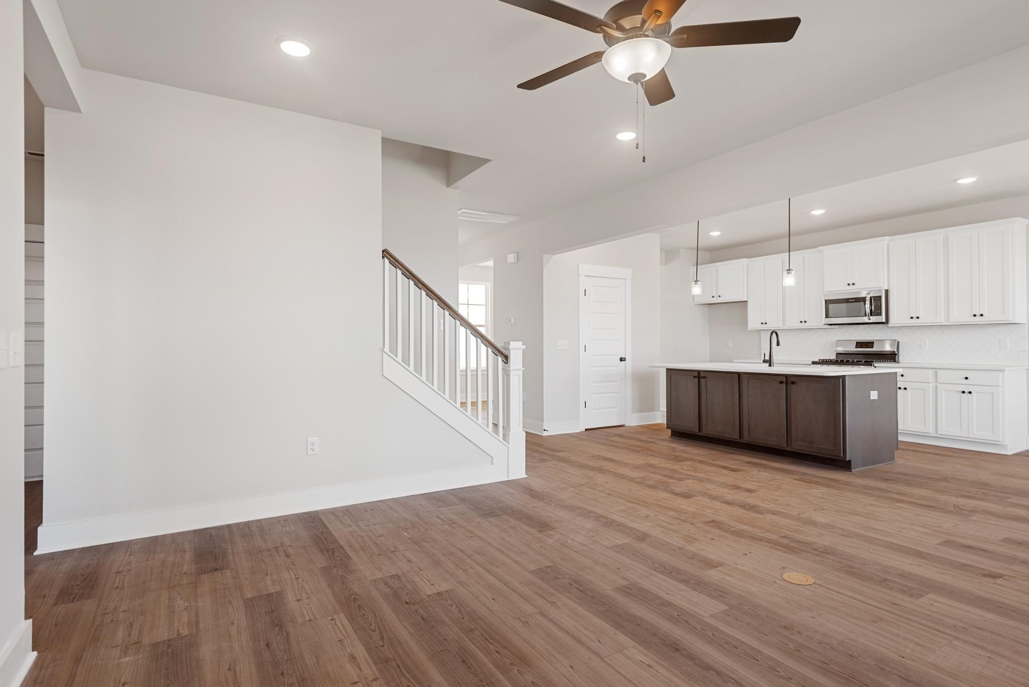 Open-concept kitchen with white cabinets, stainless appliances, dark island, and hardwood floors in Davidson Homes The Willow B, White House, TN
