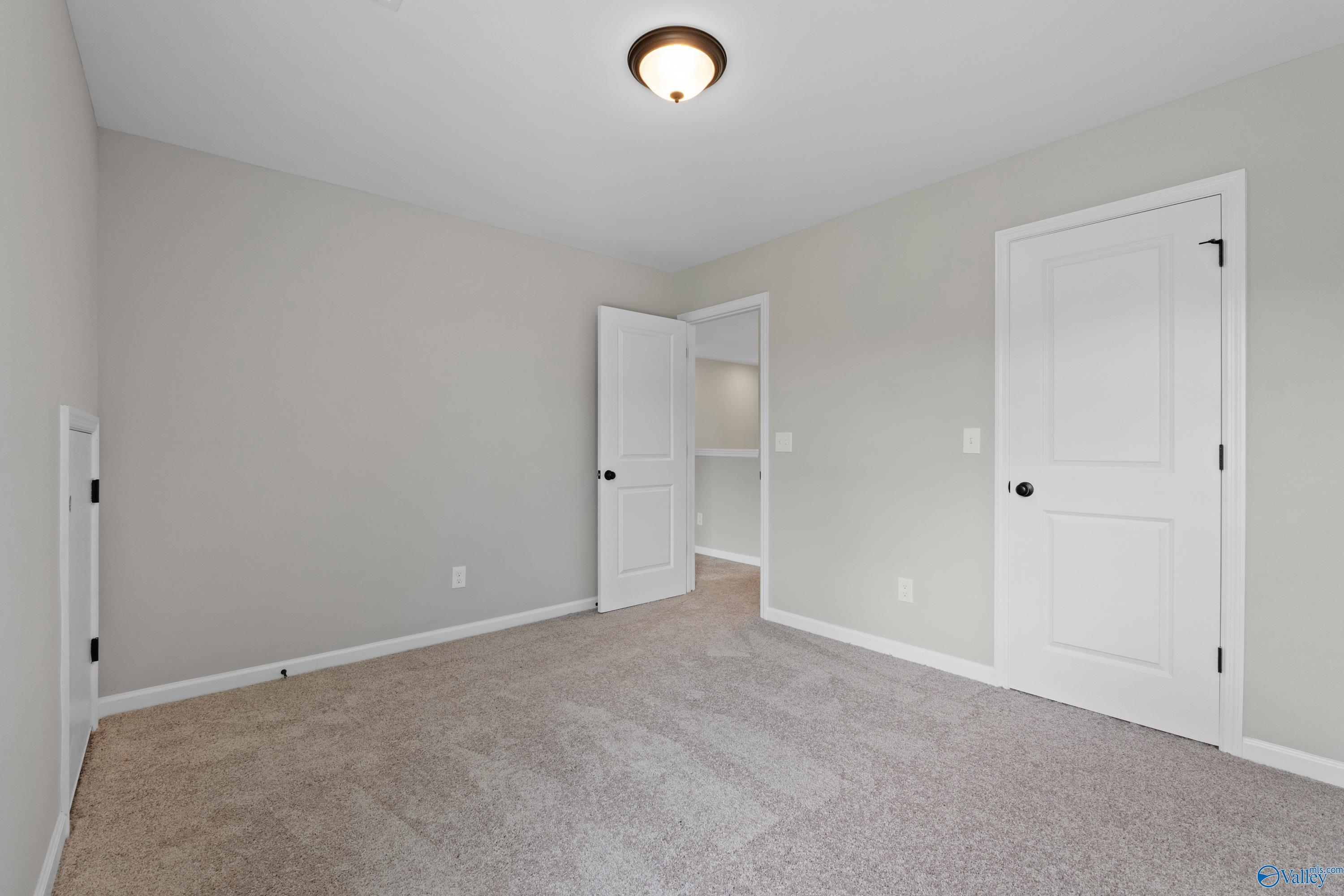 Neutral-toned secondary bedroom with beige walls, carpeted floor, white doors, and ceiling light in Davidson Homes The Dorado, Huntsville