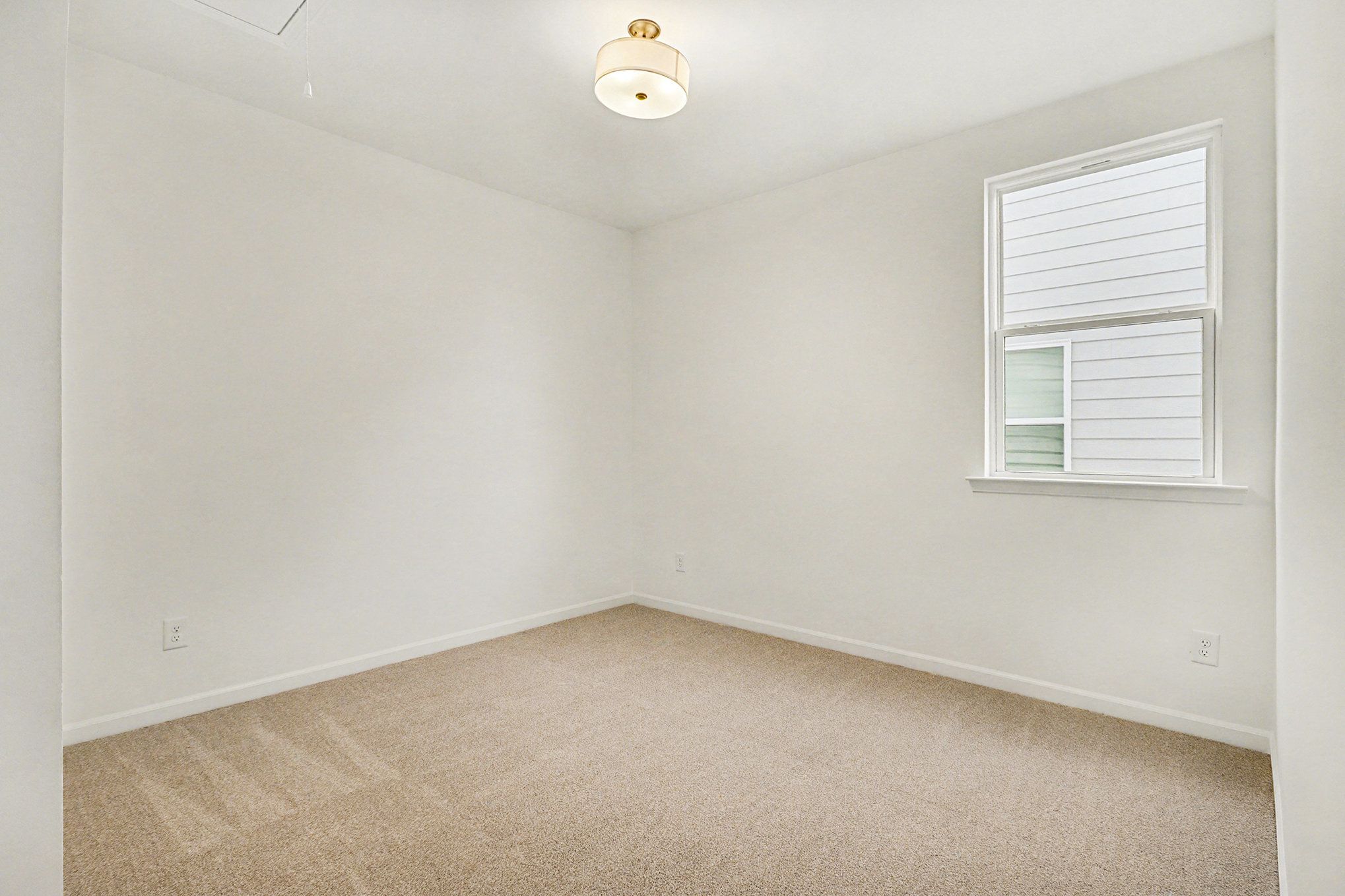 Cozy secondary bedroom with tufted gray headboard bed, rainbow duvet, nightstand lamp, and window in Davidson Homes The Daphne B, Loganville, GA