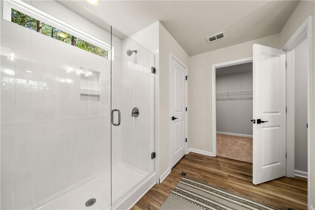 Modern master bathroom with frameless glass shower, white subway tiles, and walk-in closet in Davidson Homes The Willow B, Riverwood, Dallas, GA