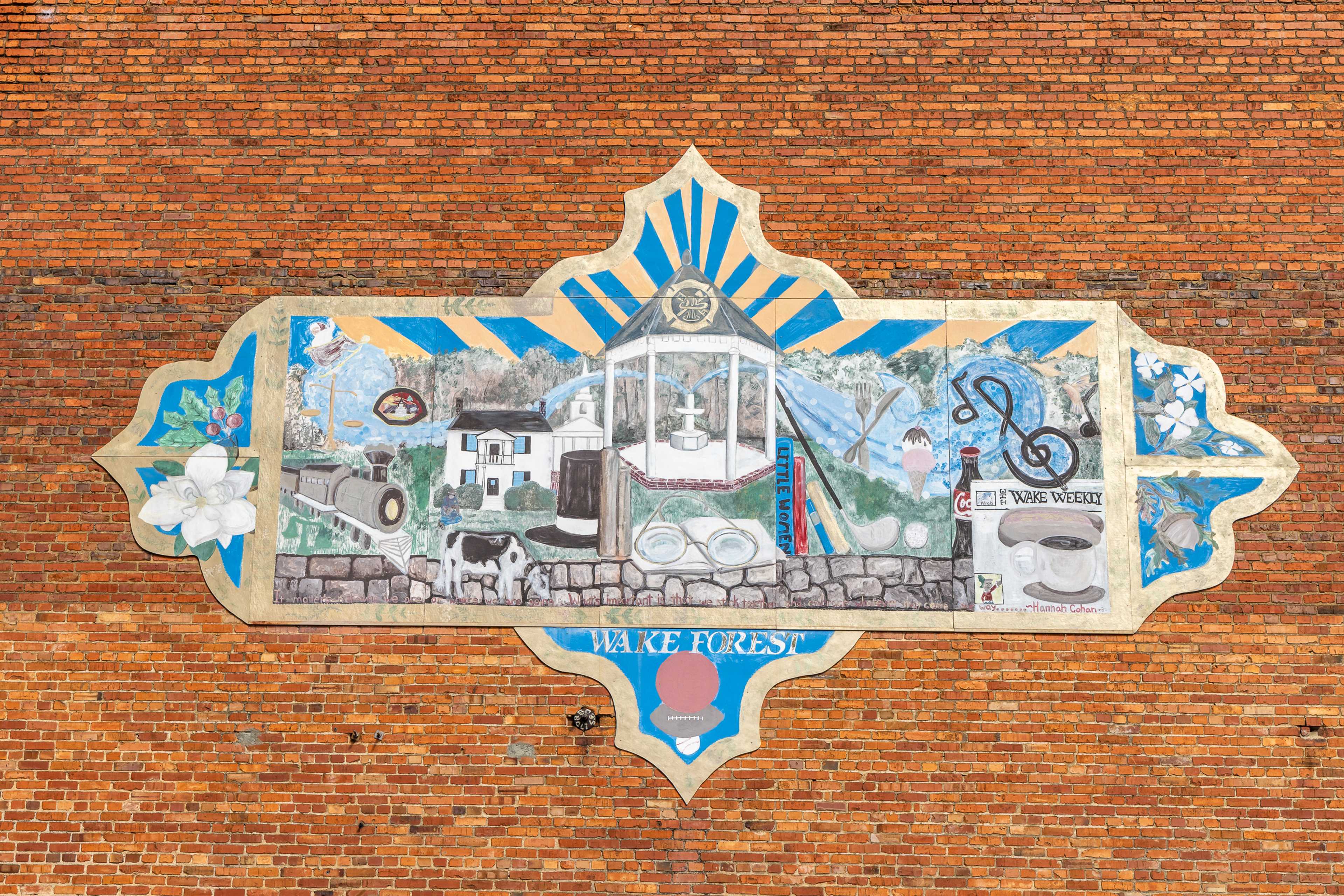 Colorful Wake Forest NC mural on brick wall with gazebo, homes, bikes, music notes and flowers at Sage on North Main