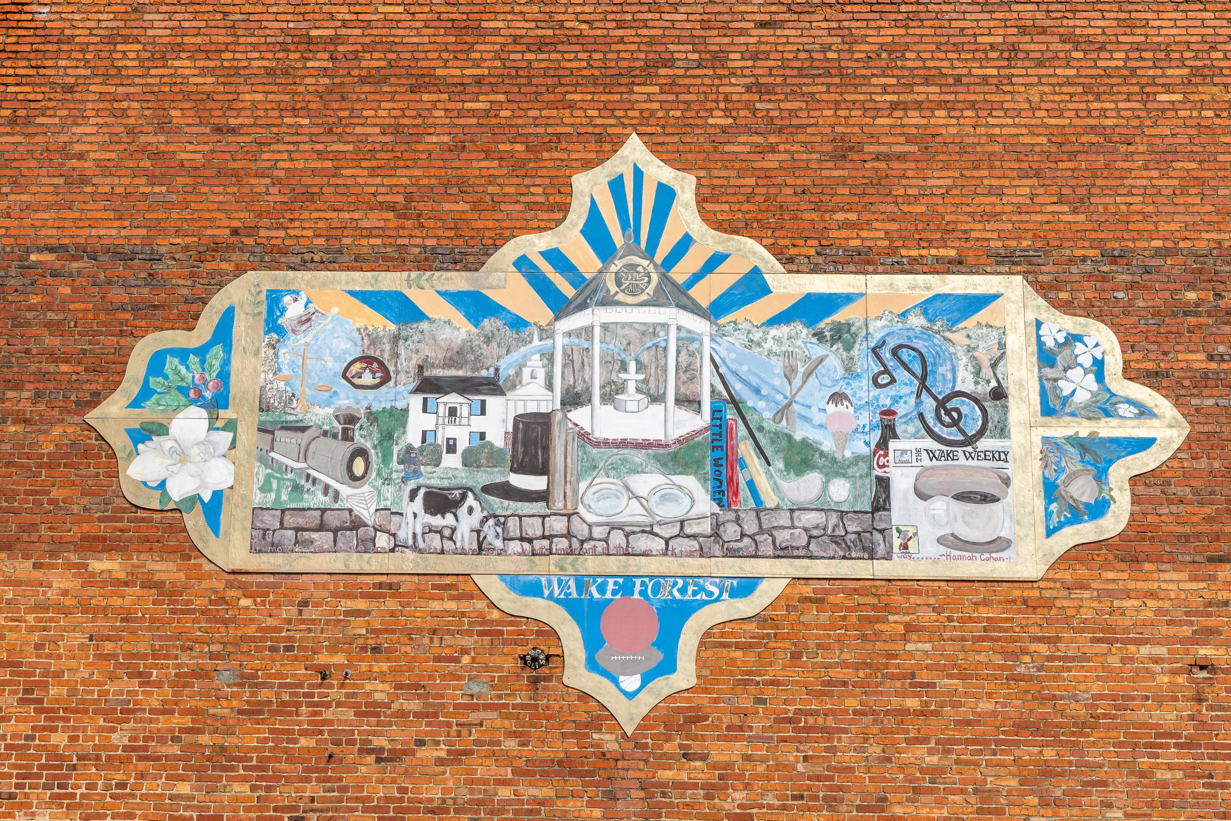 Colorful Wake Forest NC mural on brick wall with gazebo, homes, bikes, music notes and flowers at Sage on North Main