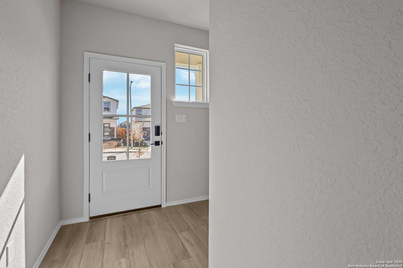 Bright front entry door with sidelight window overlooking neighborhood in Davidson Homes The Brazos C, San Antonio