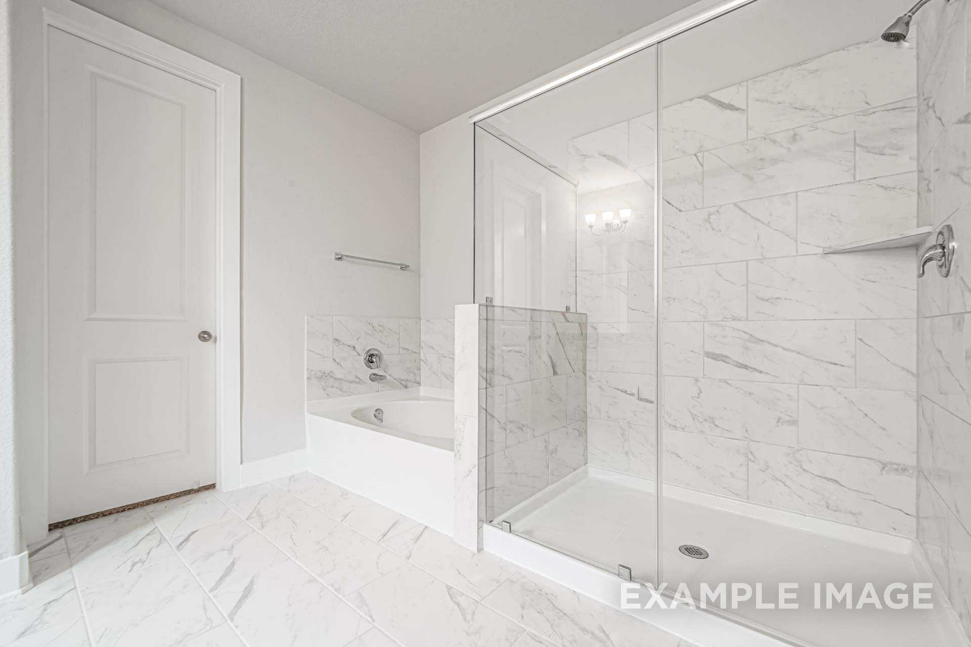 Luxurious master bathroom in The George B with white marble tiles, freestanding tub, and glass shower enclosure
