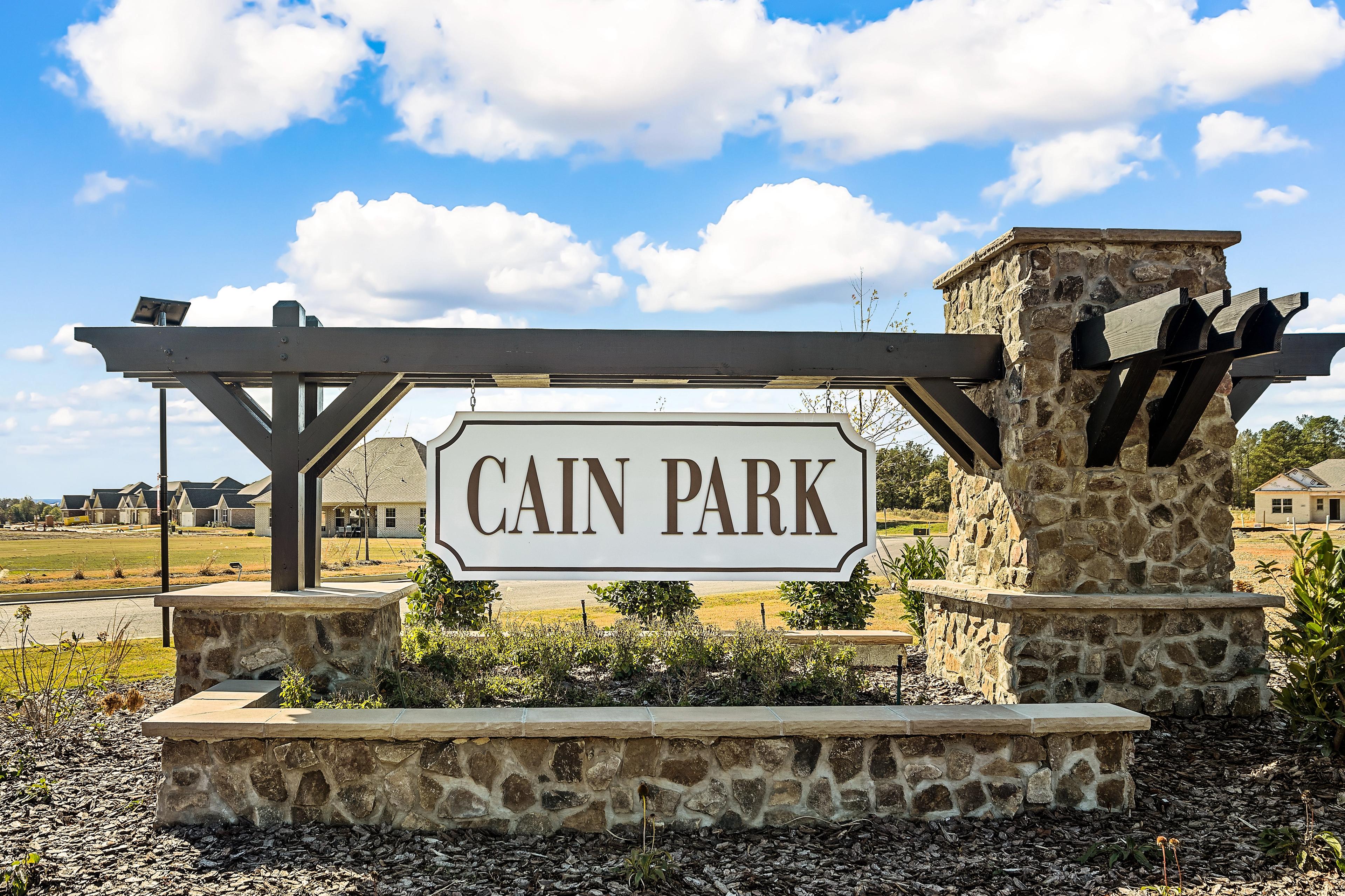 Stone entrance sign for The Retreat at Cain Park in Hartselle, Alabama with wooden archway and landscaped base