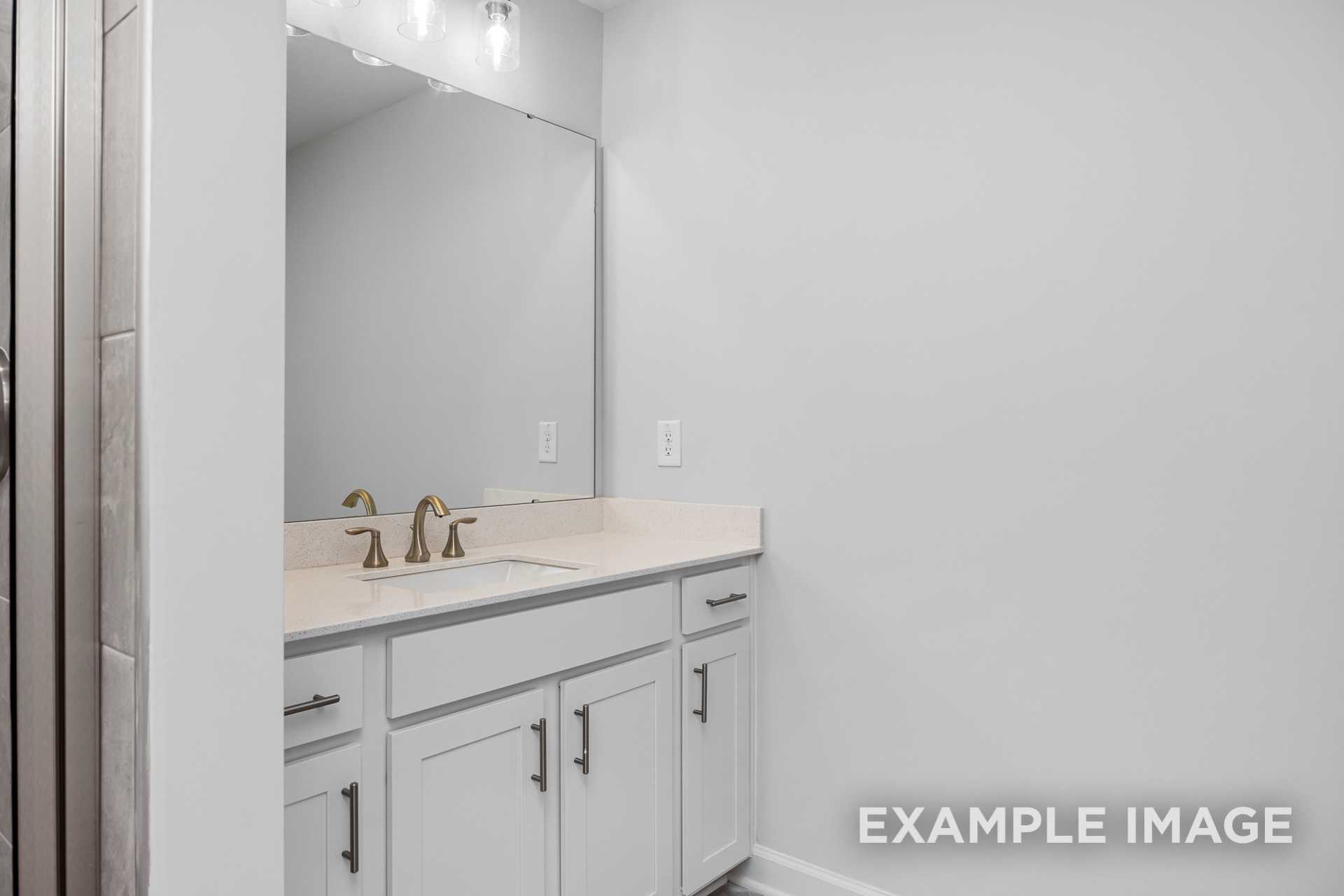 Spacious master bathroom in The Preston B with white double vanity, large mirror, and tiled shower walls