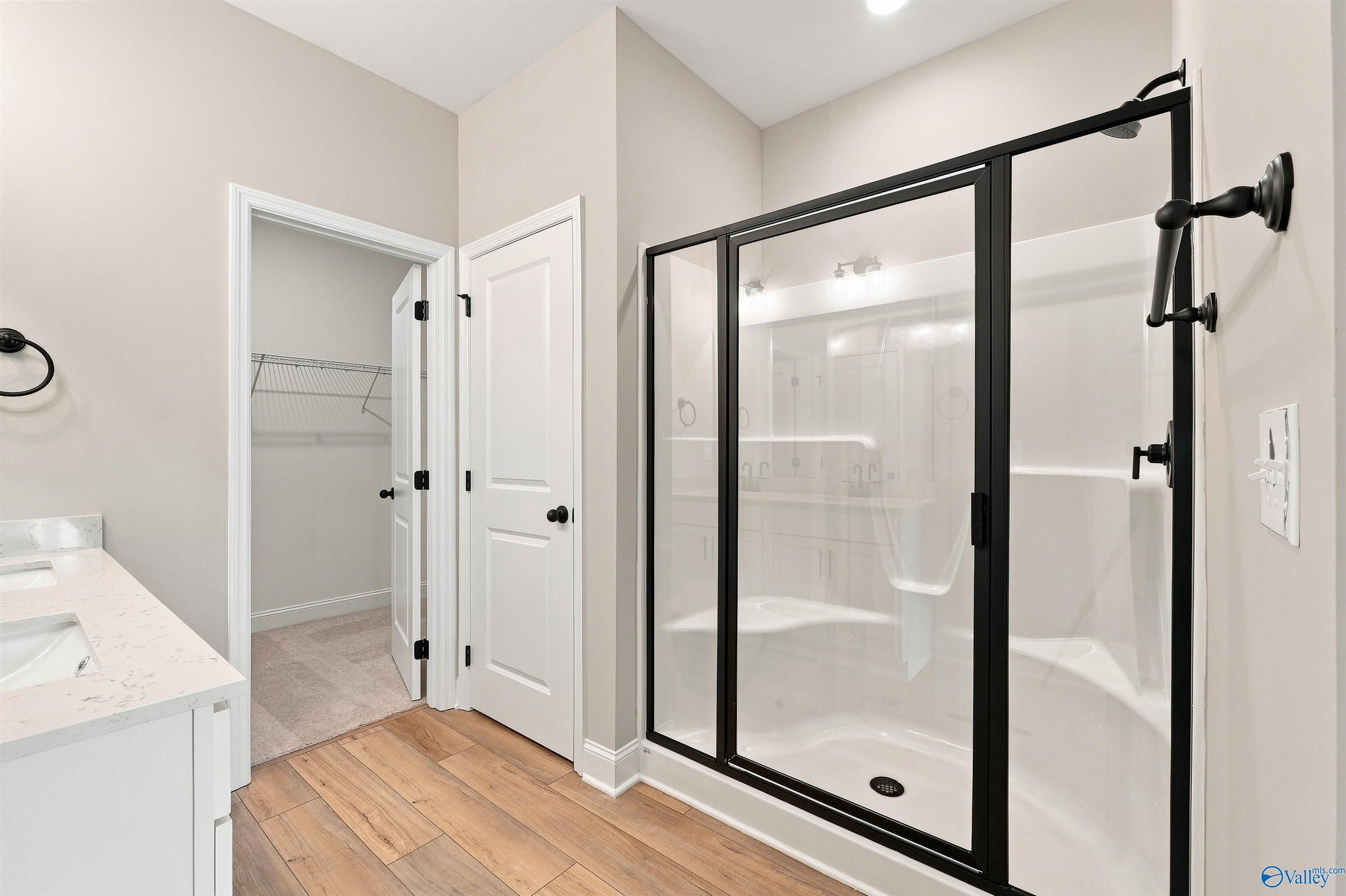 Modern master bathroom with black-framed glass shower, dual vanity, and walk-in closet in Davidson Homes Franklin C, Toney AL