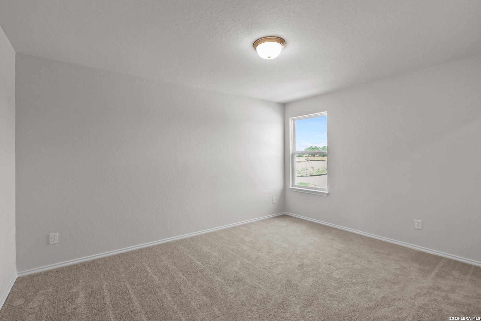 Spacious bedroom with neutral carpet and natural light in The San Marcos F floor plan by Davidson Homes, San Antonio, TX.