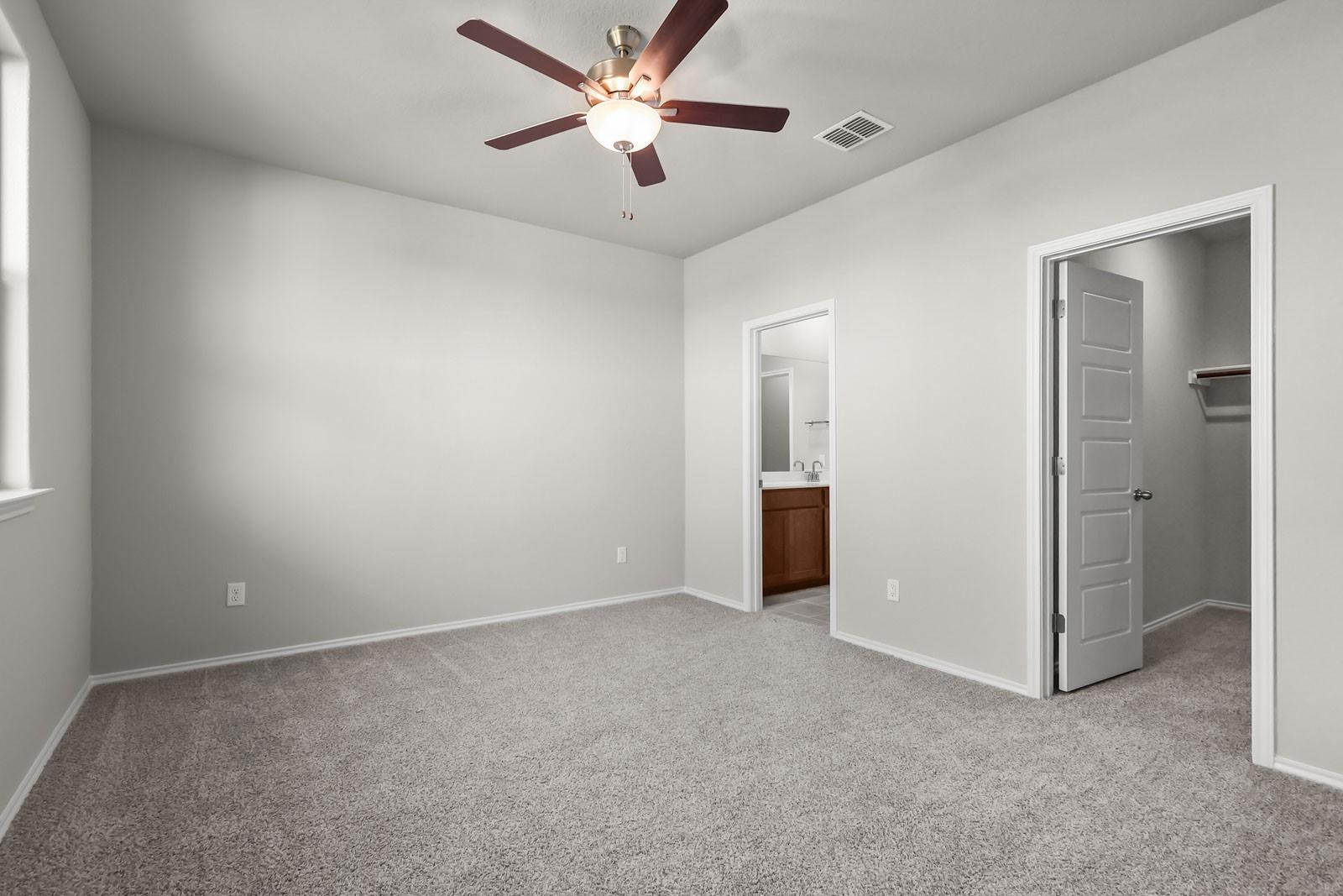 Spacious secondary bedroom with ceiling fan, ensuite bathroom, and walk-in closet in Davidson Homes The Frio G floor plan.