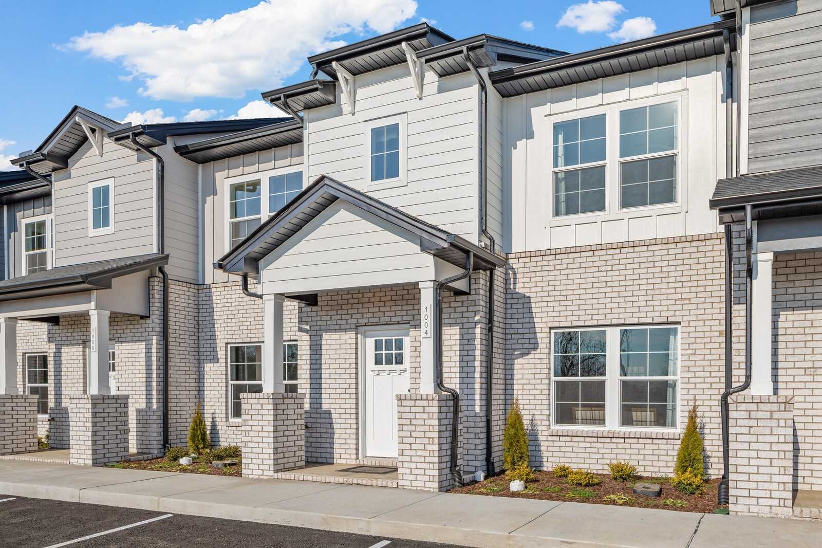 Row of modern 2-story townhomes with brick accents, covered porches, and landscaped yards in The Towns at Red River, Gallatin, Tennessee