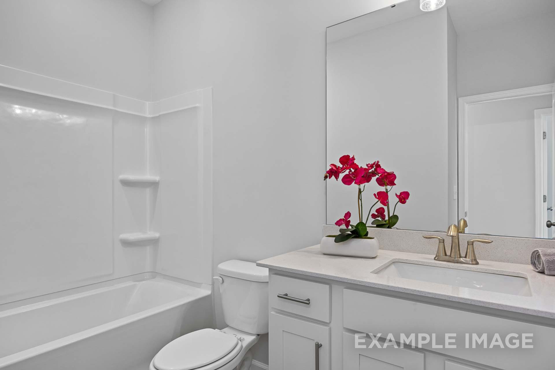 Spacious master bathroom in The Carter B by Davidson Homes with white tiled walk-in shower, soaking tub, modern vanity, and orchids